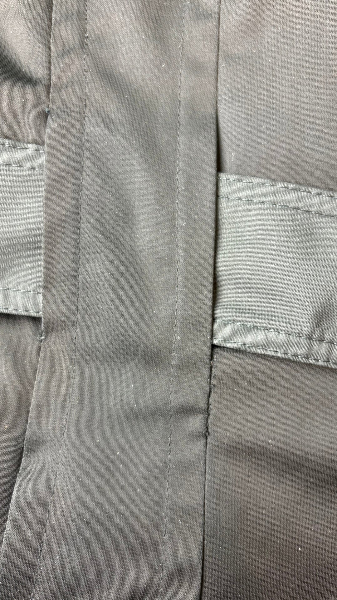 Manteau noir style trench Anne Klein, taille large. Vue de près d'une deuxième réparation près d'une ganse pour ceinture.