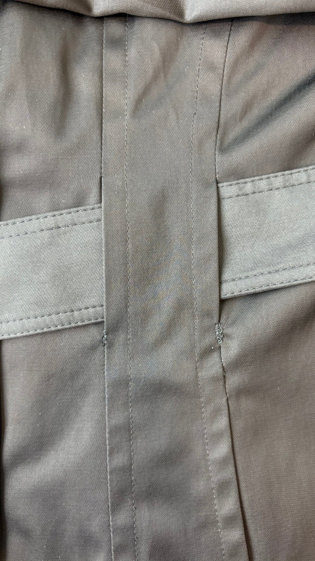 Manteau noir style trench Anne Klein, taille large. Vue de près d'une petite réparation près d'une ganse pour la ceinture.