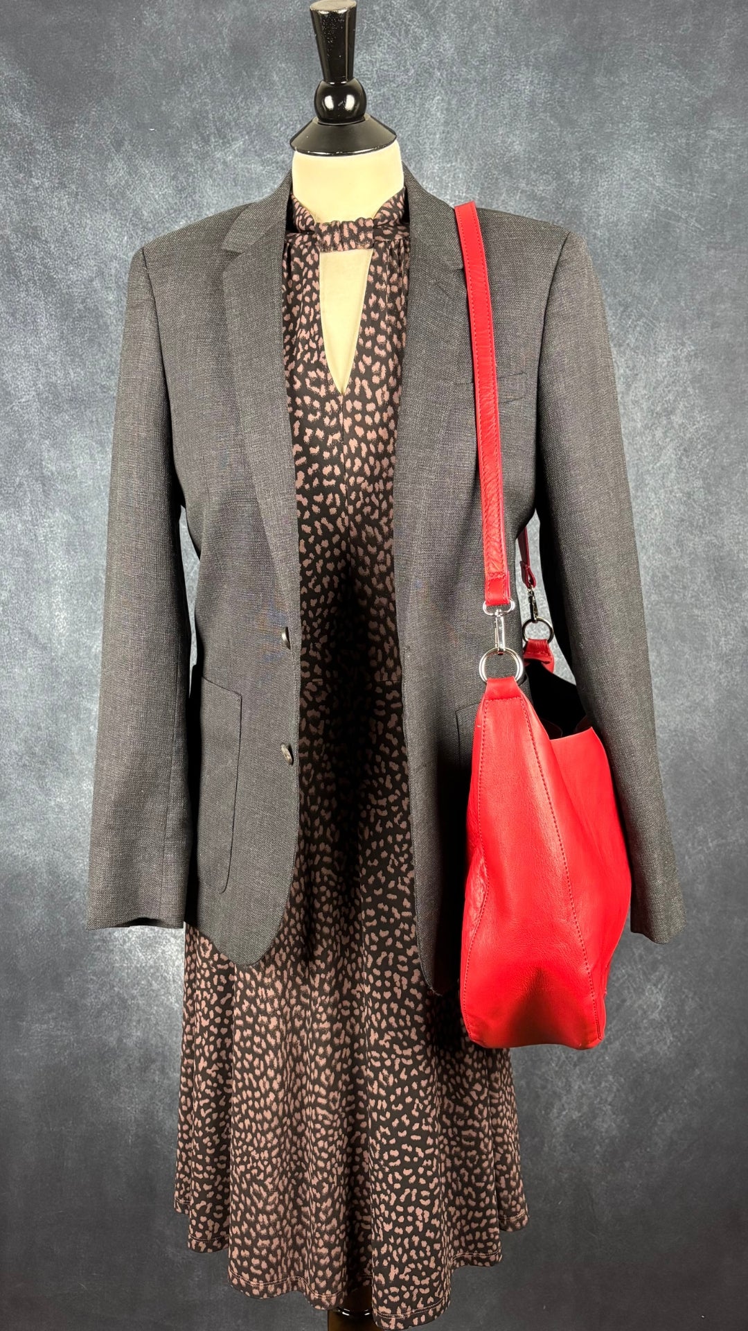 Blazer en laine gris foncé légèrement bleuté, Sandro taille estimée à small. Vue de l'agencement avec le sac à main en cuir rouge et la robe à motifs animaliers Michael Kors.
