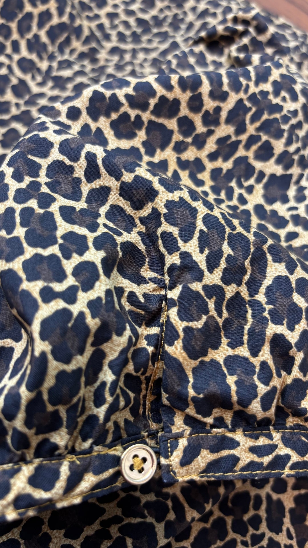 Blouse léopard en popeline de coton J.Crew, taille medium. Vue de près du bouton à l'ourlet de la manche.
