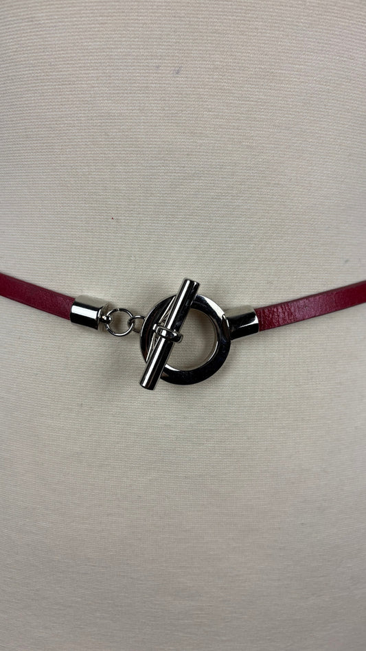 Ceinture en cuir rouge taille unique. Vue de près de la boucle, sur le mannequin.