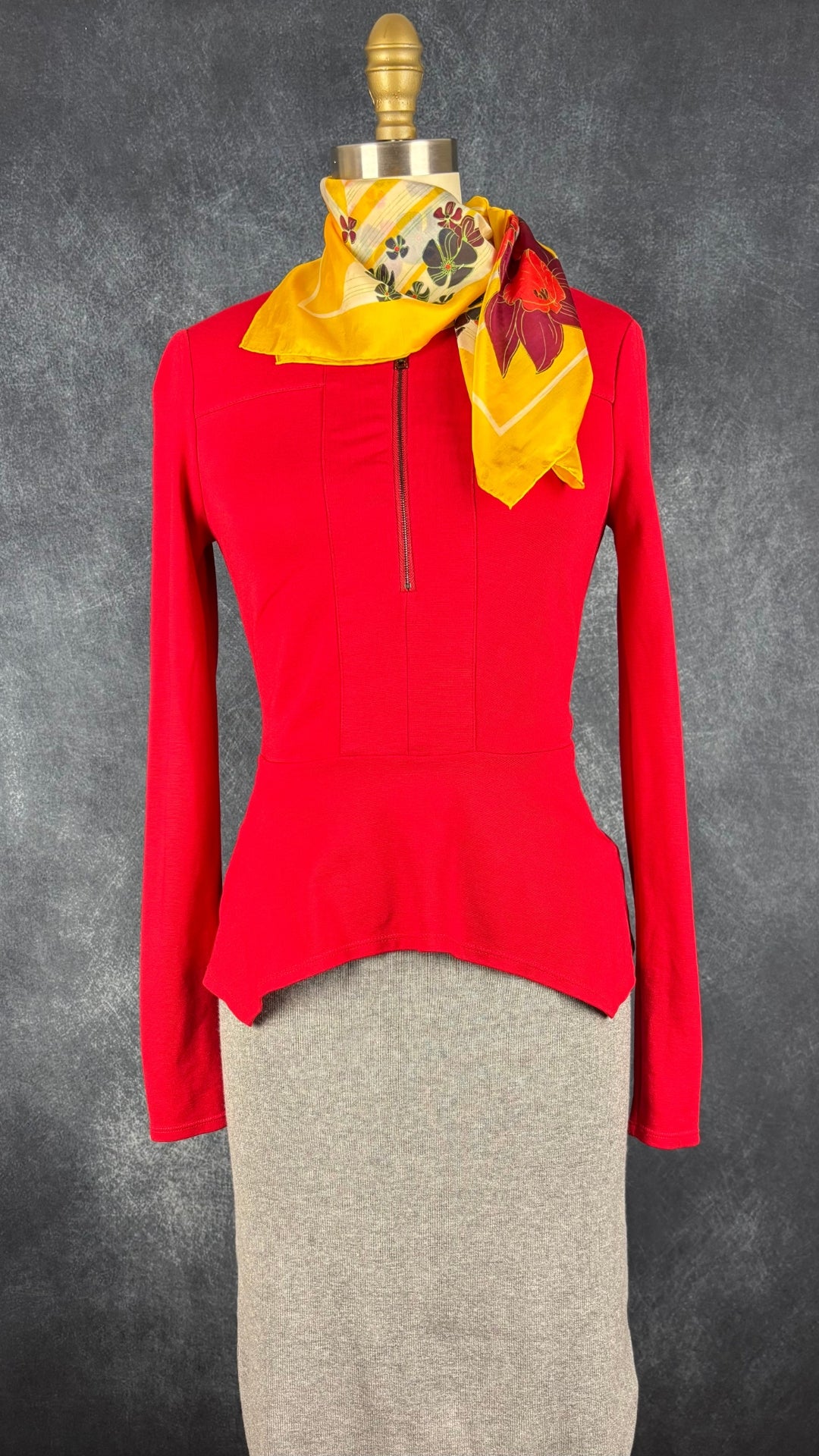 Chandail rouge en ponte à ourlet péplum asymétrique BCBG MaxAzria, taille xs. Vue de l'agencement avec la jupe en tricot gris pâle et le foulard floral en soie.