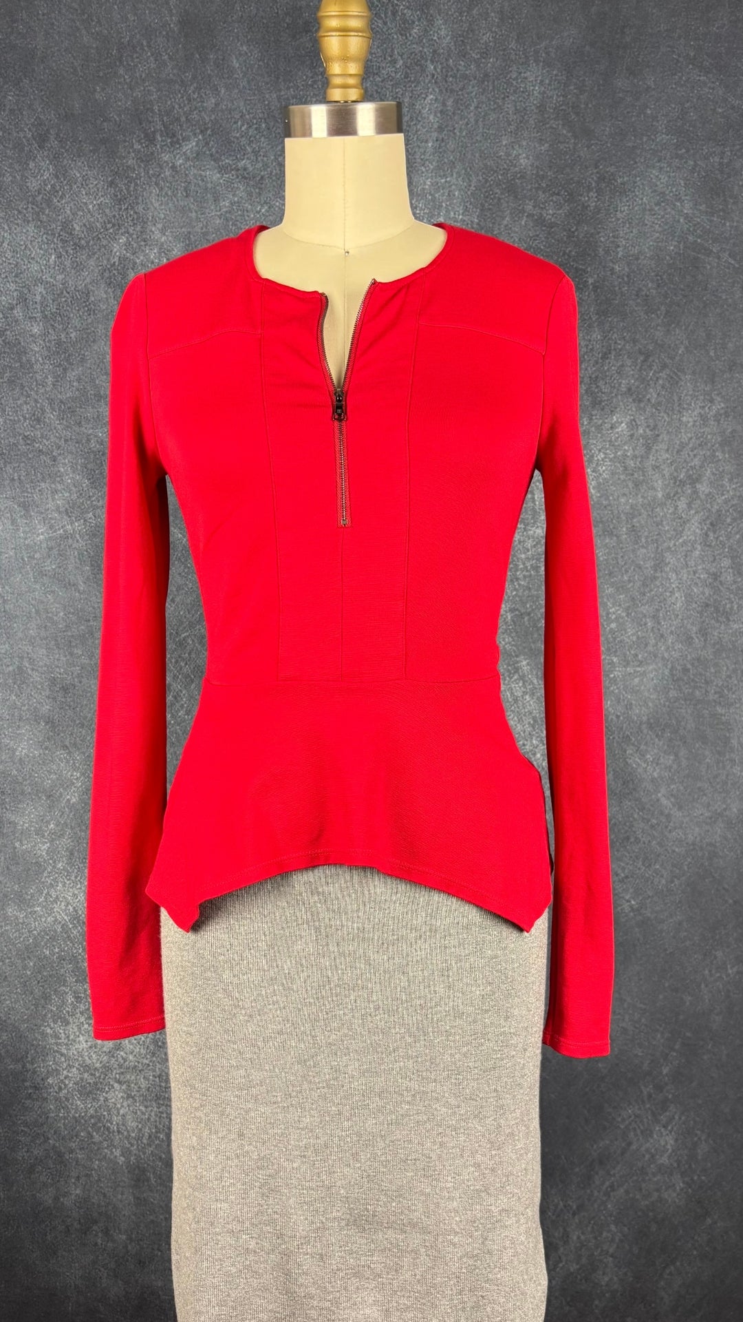 Chandail rouge en ponte à ourlet péplum asymétrique BCBG MaxAzria, taille xs. Vue de l'agencement avec la jupe en tricot gris pâle.