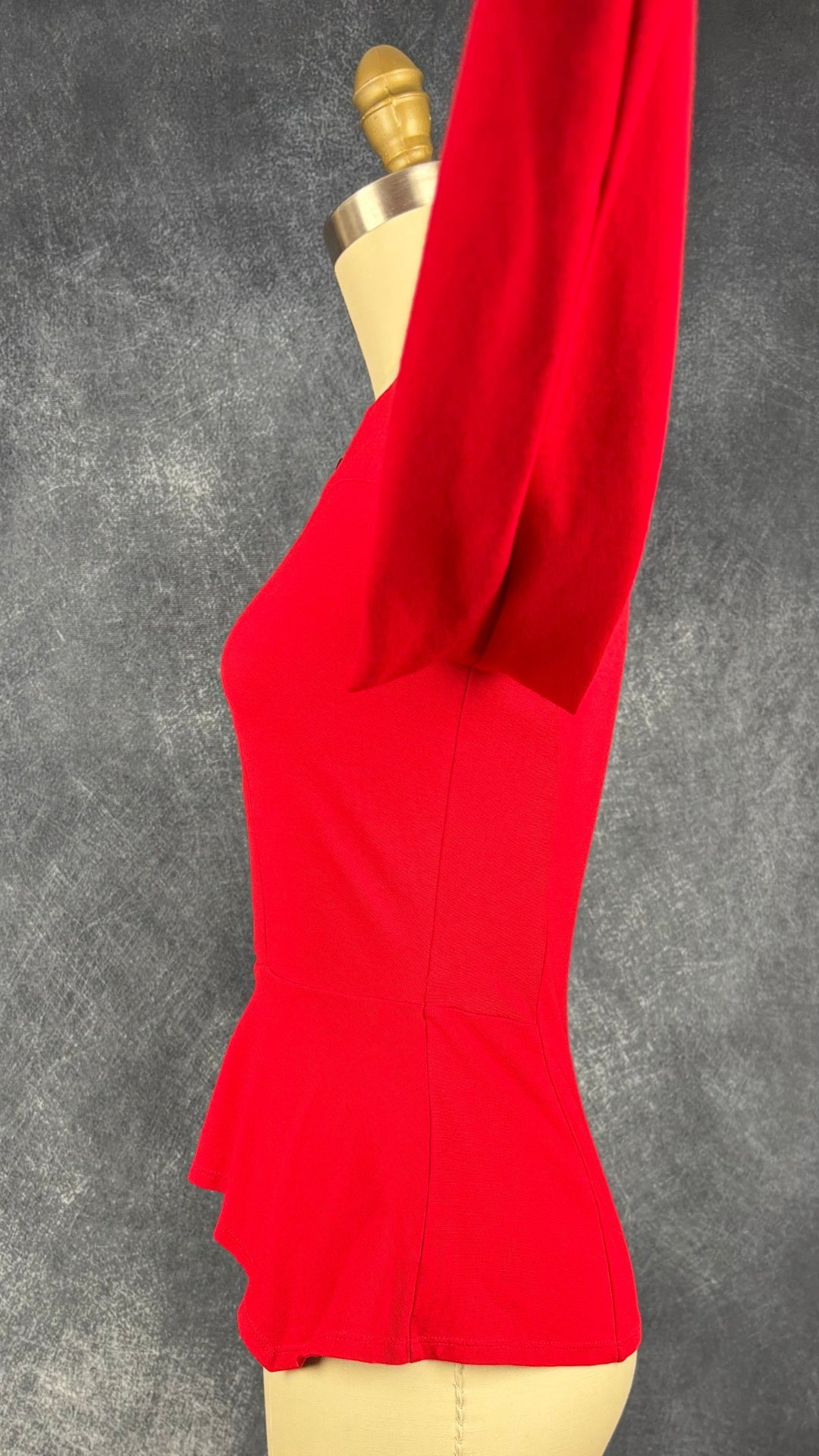 Chandail rouge en ponte à ourlet péplum asymétrique BCBG MaxAzria, taille xs. Vue de côté, manche relevée.