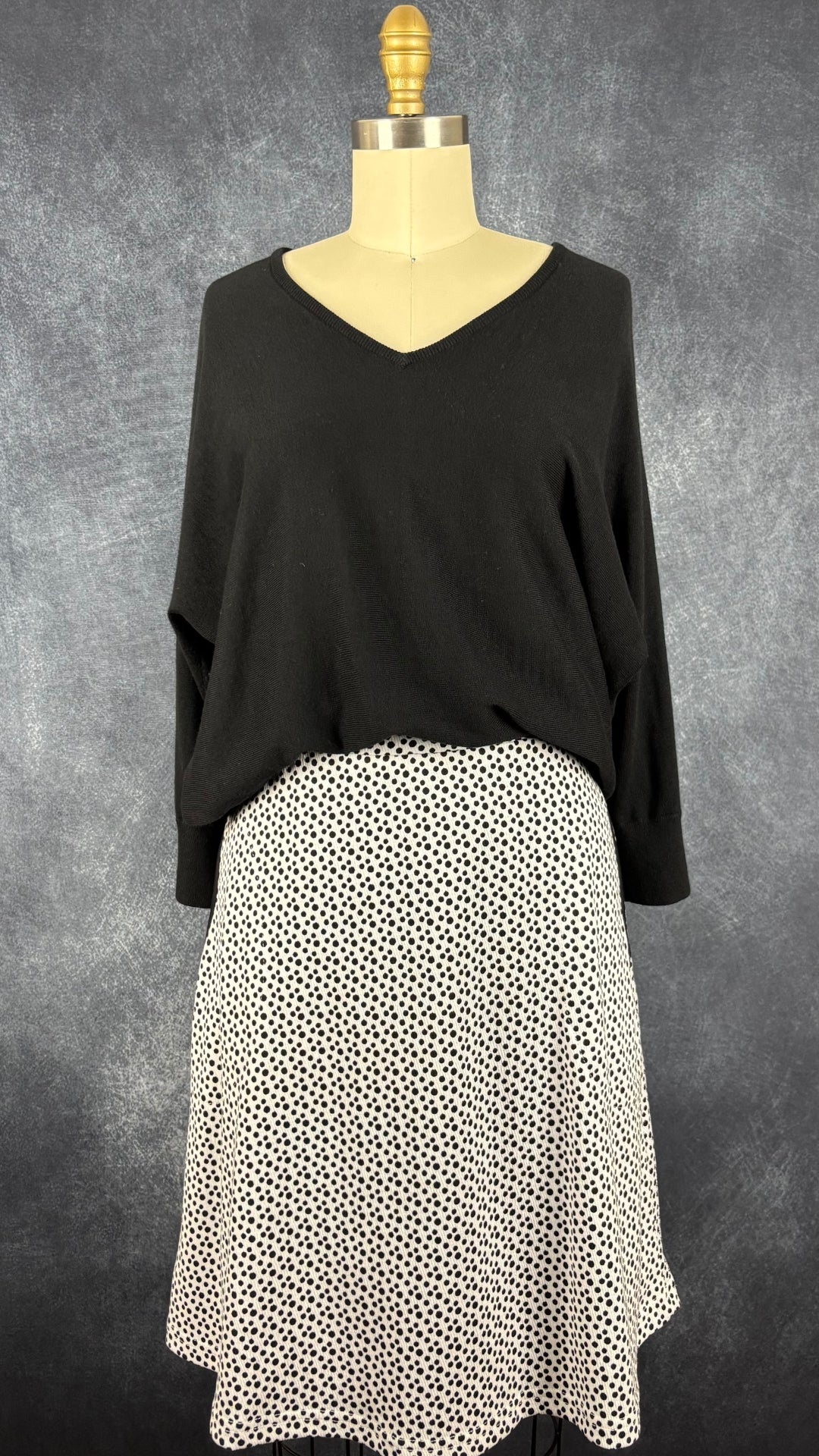 Chandail en tricot noir à col en V et dos boutonné Repeat, taille 38 (s/m). Vue de l'agencement avec la jupe à pois Dinh Bá.