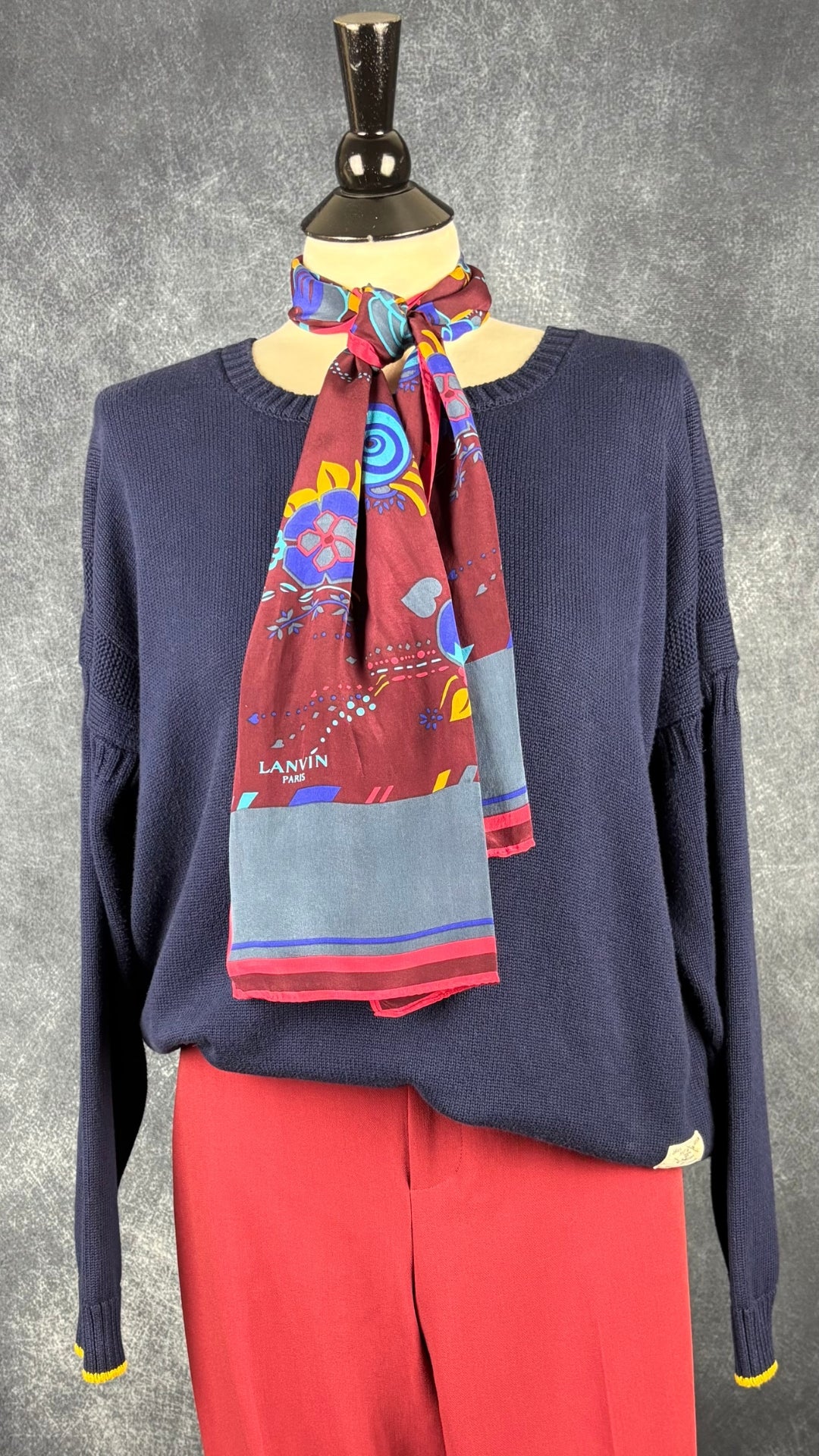 Foulard rectangulaire long Lanvin Paris, motifs floraux aux couleurs automnales. Vue de l'agencement avec le tricot de coton marine et le pantalon rouge brique Part Two.