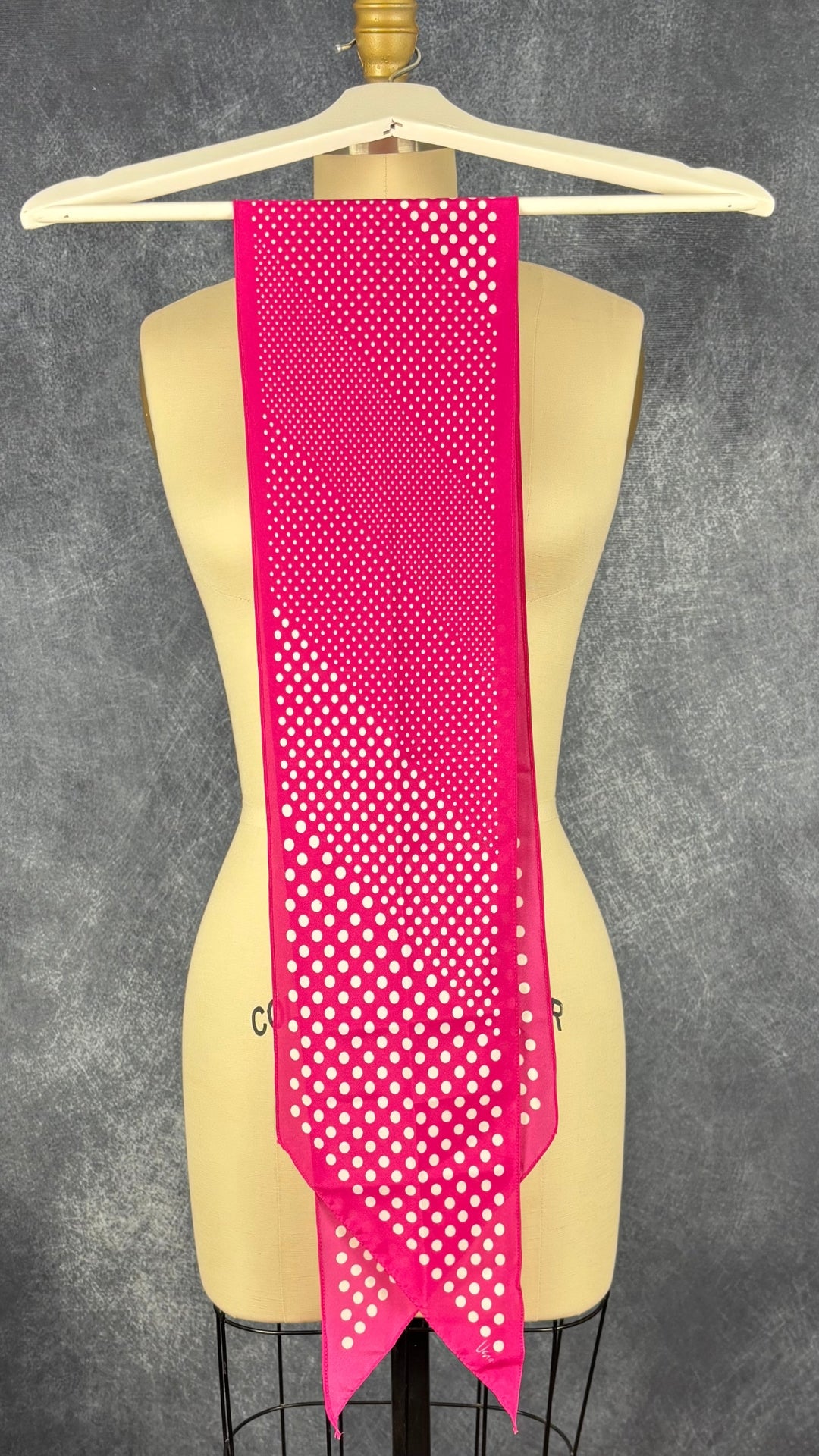 Foulard rose étroit à extrémités en pointe à pois blanc Vera. Vue du foulard plié en deux sur le cintre.