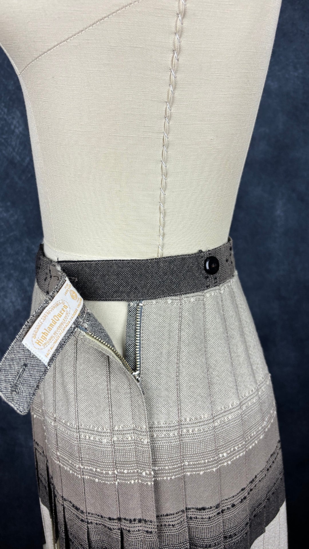 Jupe plissée vintage à carreaux réversible en laine Highland Queen, taille estimée à xs. Vue de la bande de taille composée de 2 boutons et d'une fermeture à glissière réversible YKK.
