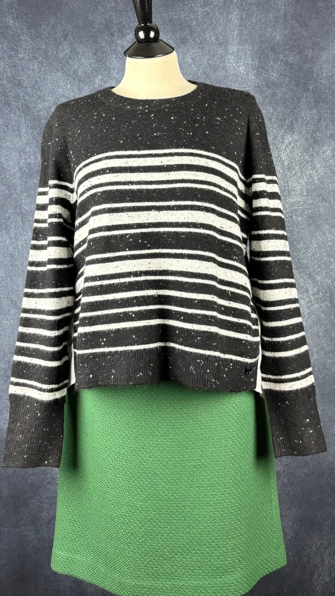 Jupe verte en pure laine vierge Contemporaine, taille estimée à large. Vue de l'agencement avec le chandail en tricot à rayures et dos fluide.