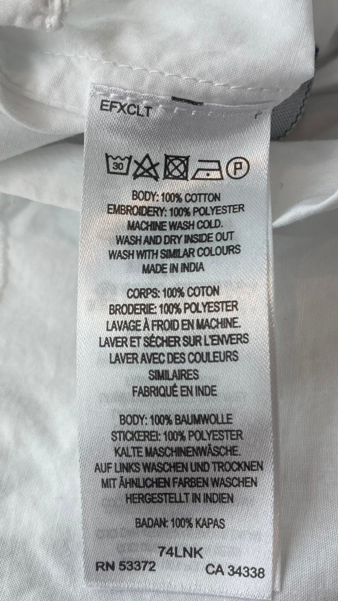 Pantalon très ample blanc style jupe avec broderie anglaise au bas des jambes. Marque French Connection, taille extra small, équivalent à 4. Vue de l'étiquette de composition et entretien.