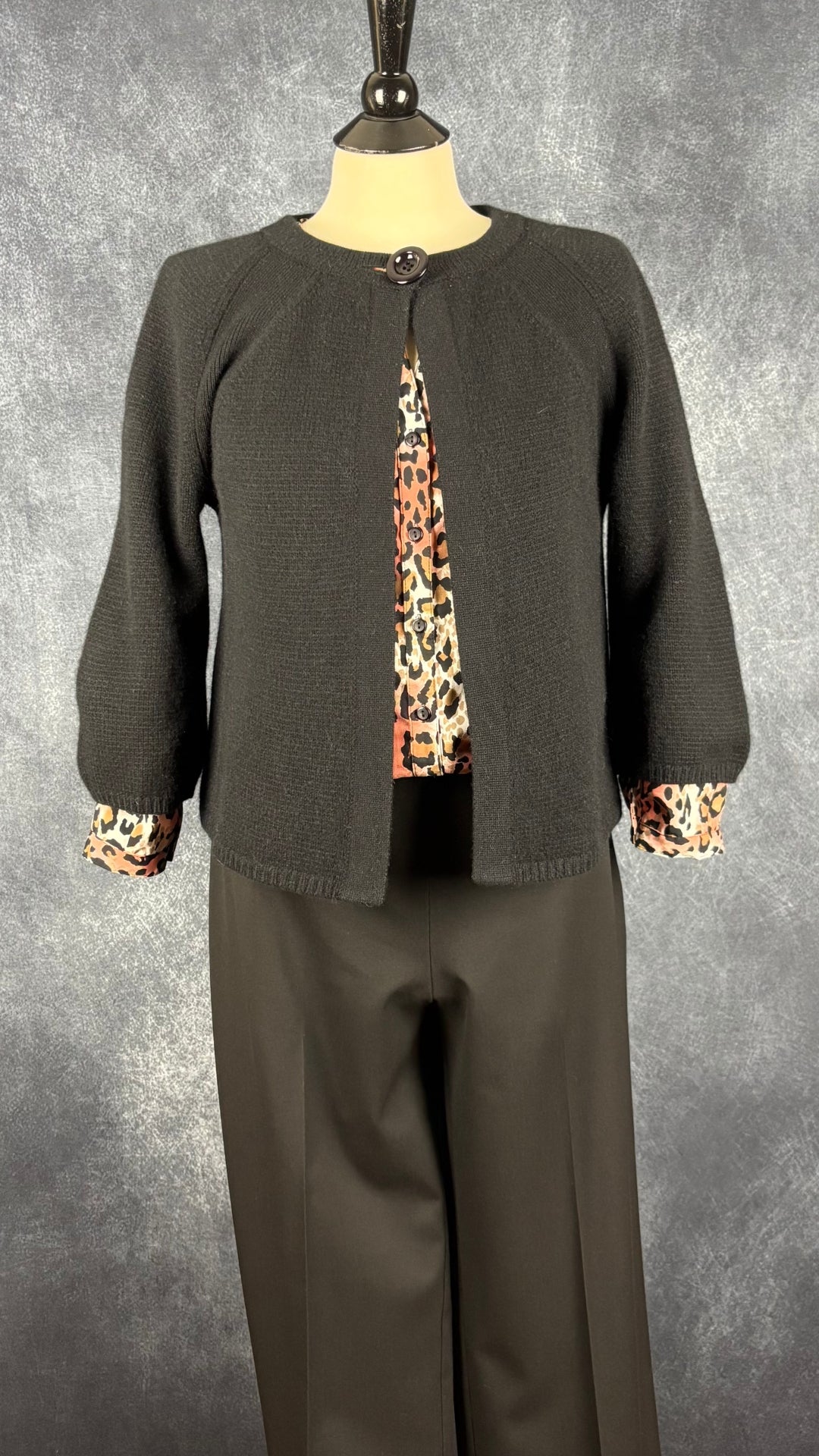 Pantalon noir jambe large à revers Sarah Pacini, taille estimée à large. Vue de l'agencement avec la blouse léopard colorée et la veste en cachemire.