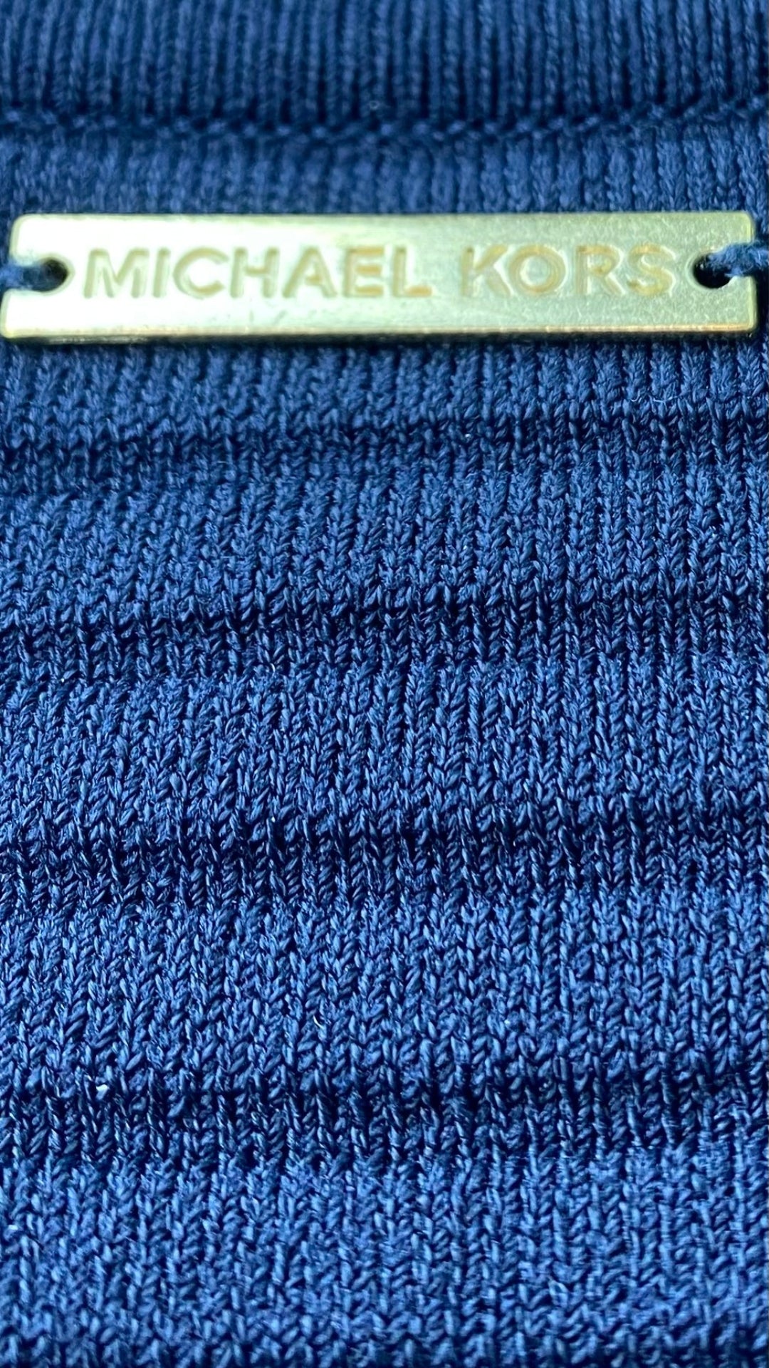 Robe marine en tricot à l'ourlet plissé Michael Kors, taille large. Vue du détail métallique au dos de la robe.