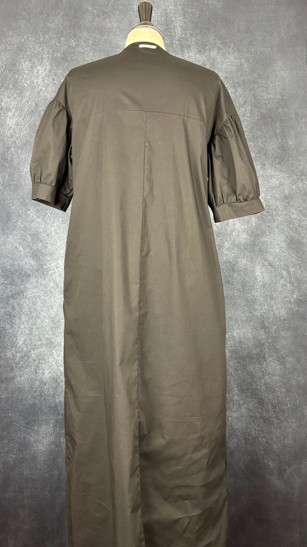 Robe noire longue à petite manche bouffante Humility, taille estimée à large. Vue de dos.