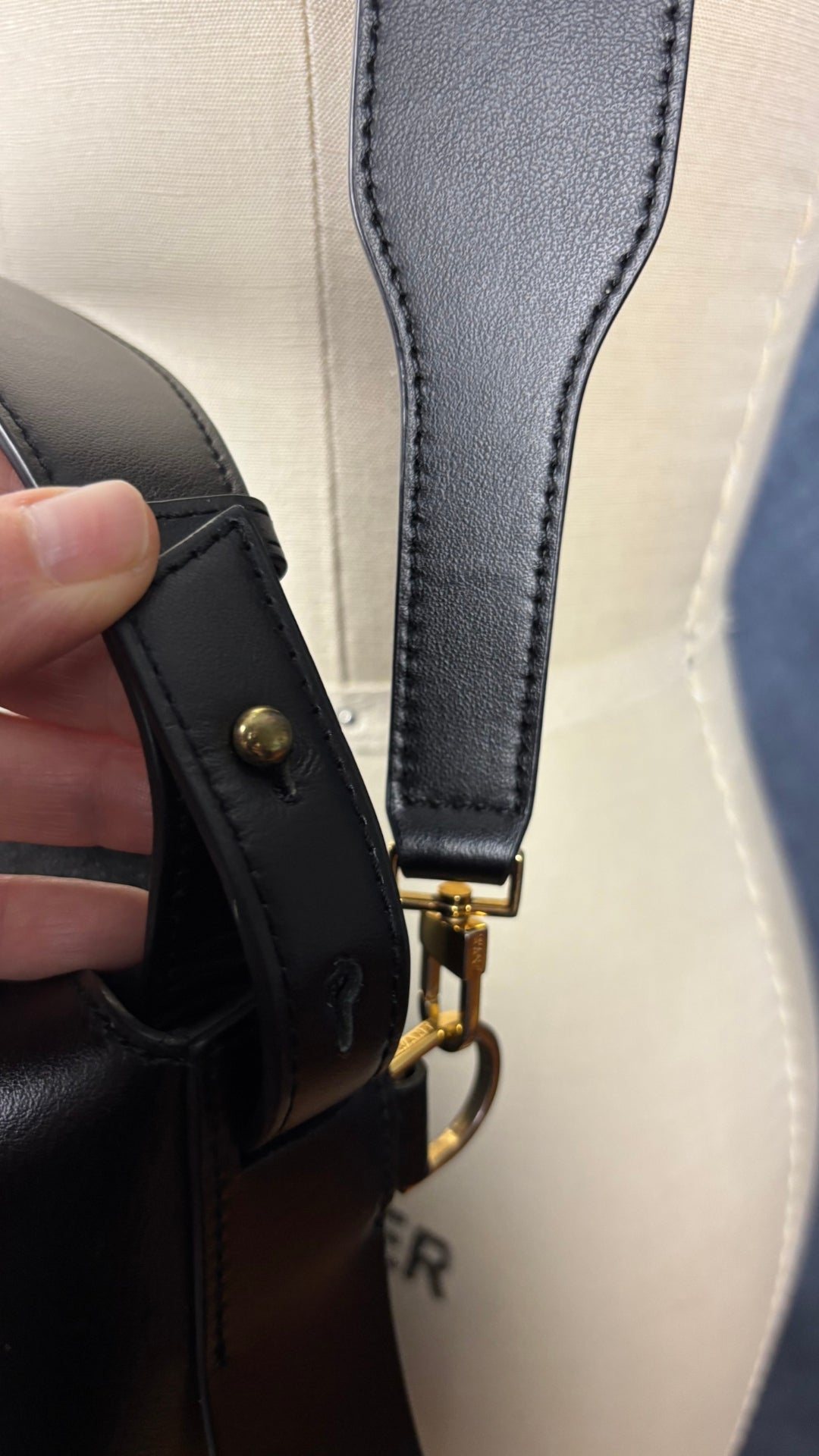 Sac sceau noir à poignée et bandoulière en cuir Want Les Essentiels. Vue de près de l'ajustement possible de la poignée.