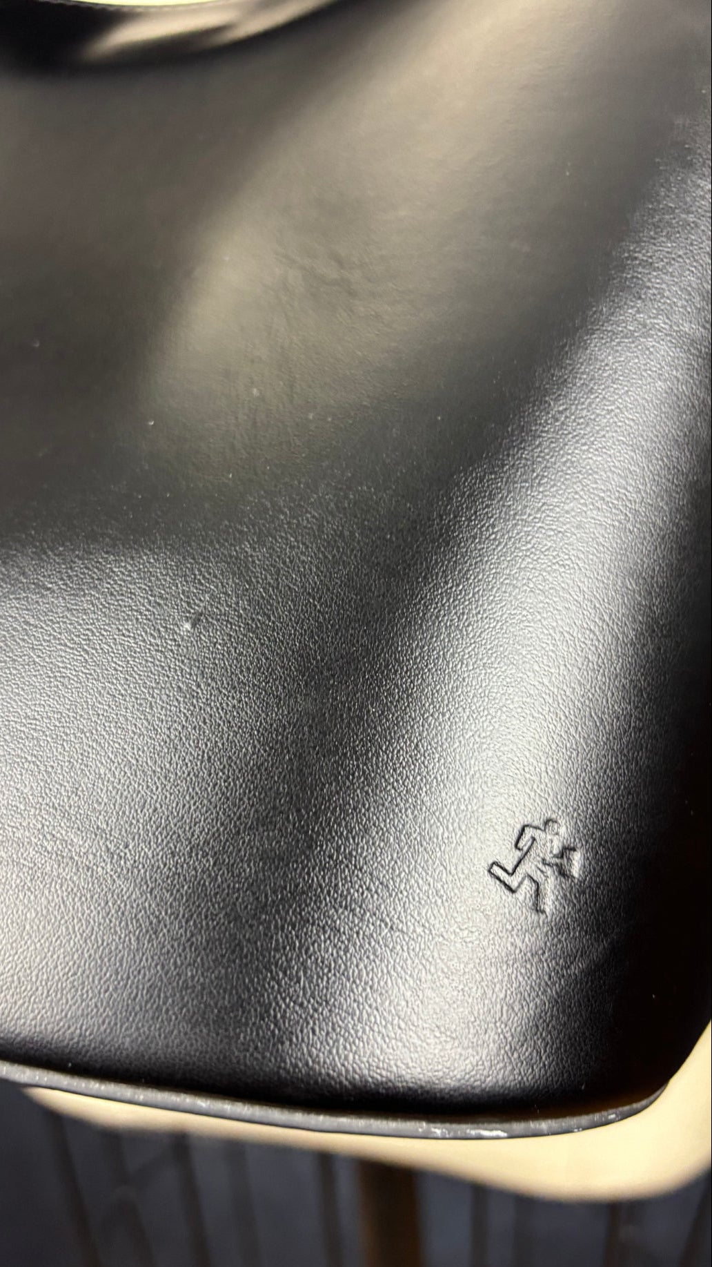 Sac sceau noir à poignée et bandoulière en cuir Want Les Essentiels. Vue du logo gravé au dos du sac.