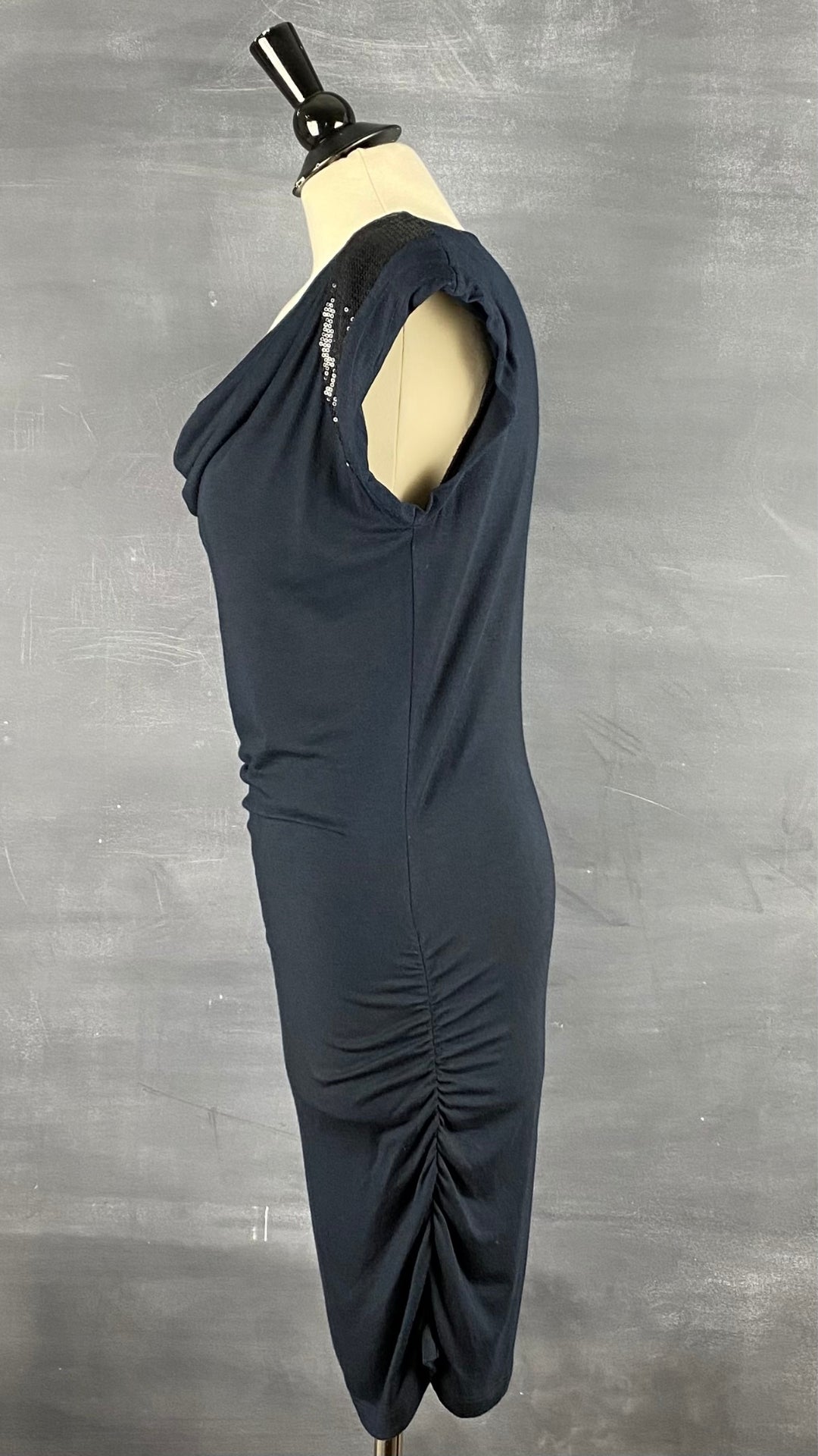 Robe ajustée et froncée sur les côtés avec un col baveux et des manches ornées de paillettes. Vue de côté.