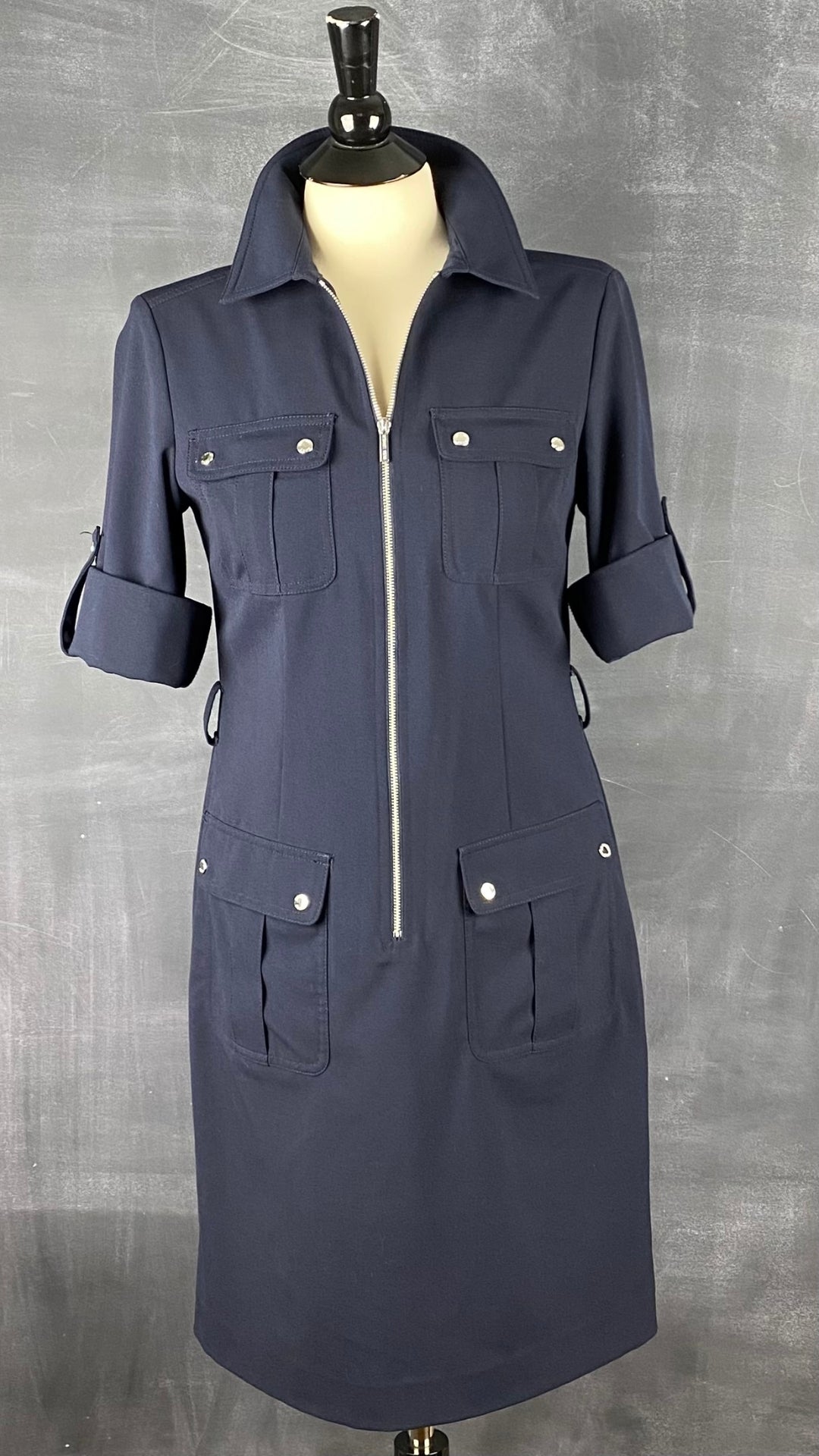 Robe utilitaire marine Michael Kors. Polyvalente et facile à agencer, cette robe est une base de la garde-robe. Vue de face, col relevé et manches roulées.