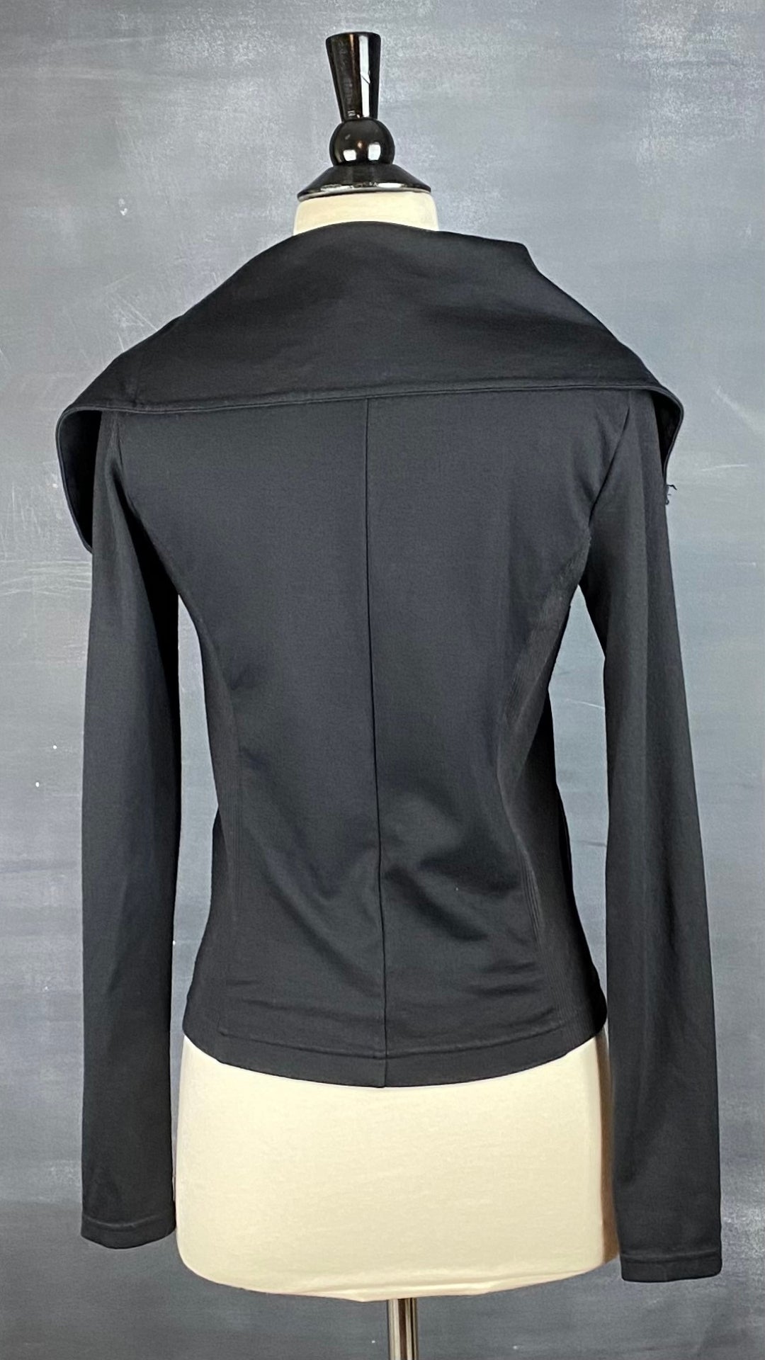 Veste noire à grand col zippé, légèrement décentré. Vue de dos.