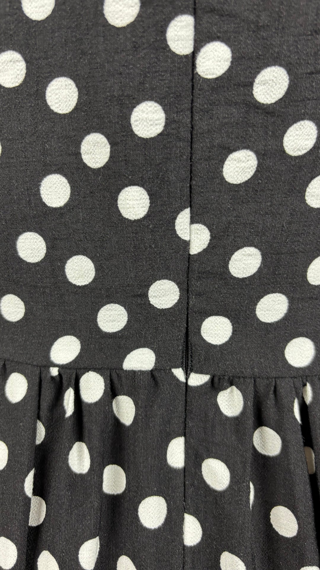 Robe longue maxi noire à pois blancs Mimz, taille medium. Vue de la petite section qui baîlle près de la taille au niveau de la fermeture à glissière.