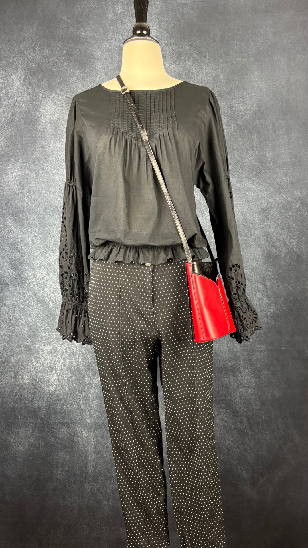 Blouse noire romantique à manches ballons et broderie anglaise aux manches, Gap, taille small. Vue de l'agencement avec le pantalon à pois Cambio et le sac à main rouge et noir en cuir.
