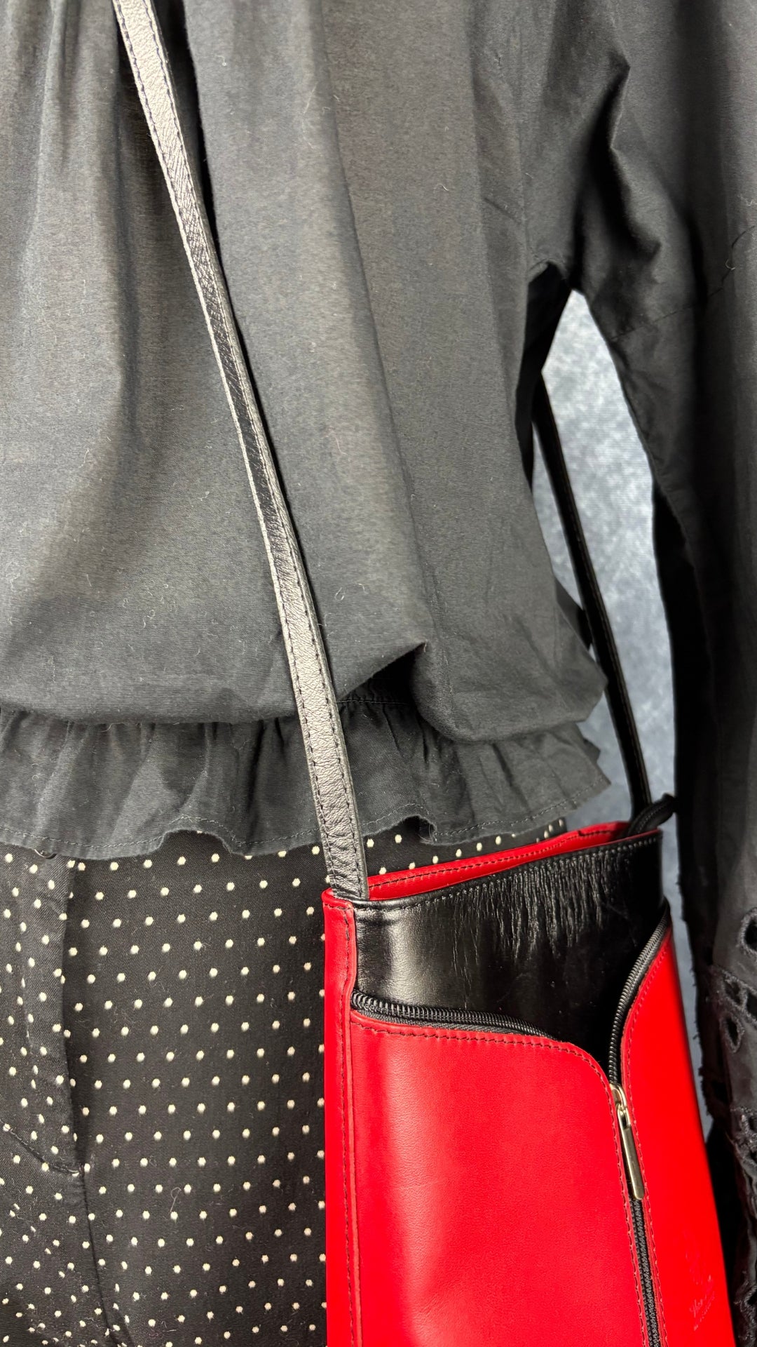 Blouse noire romantique à manches ballons et broderie anglaise aux manches, Gap, taille small. Vue de près de l'agencement de la blouse avec le pantalon à pois Cambio et le sac à main rouge et noir.