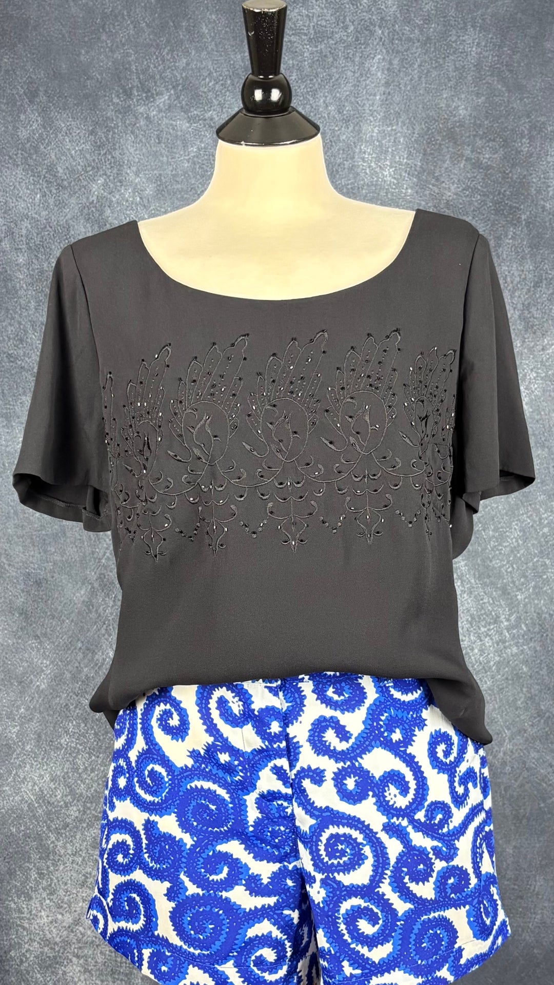 Blouse noire en soie Luisa Spagnoli, taille 52 (environ l/xl). Vue de l'agencement avec le short à motifs Tristan.