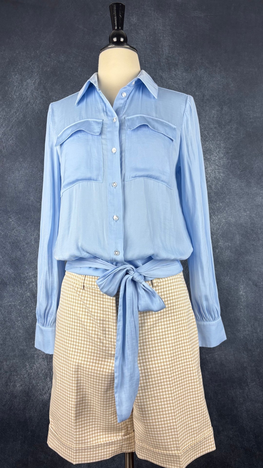 Blouse satinée bleu doux à taille soulignée de deux bandes de tissu à nouer, Tristan, taille xs. Vue de l'agencement avec le bermuda beige vichy Tristan.