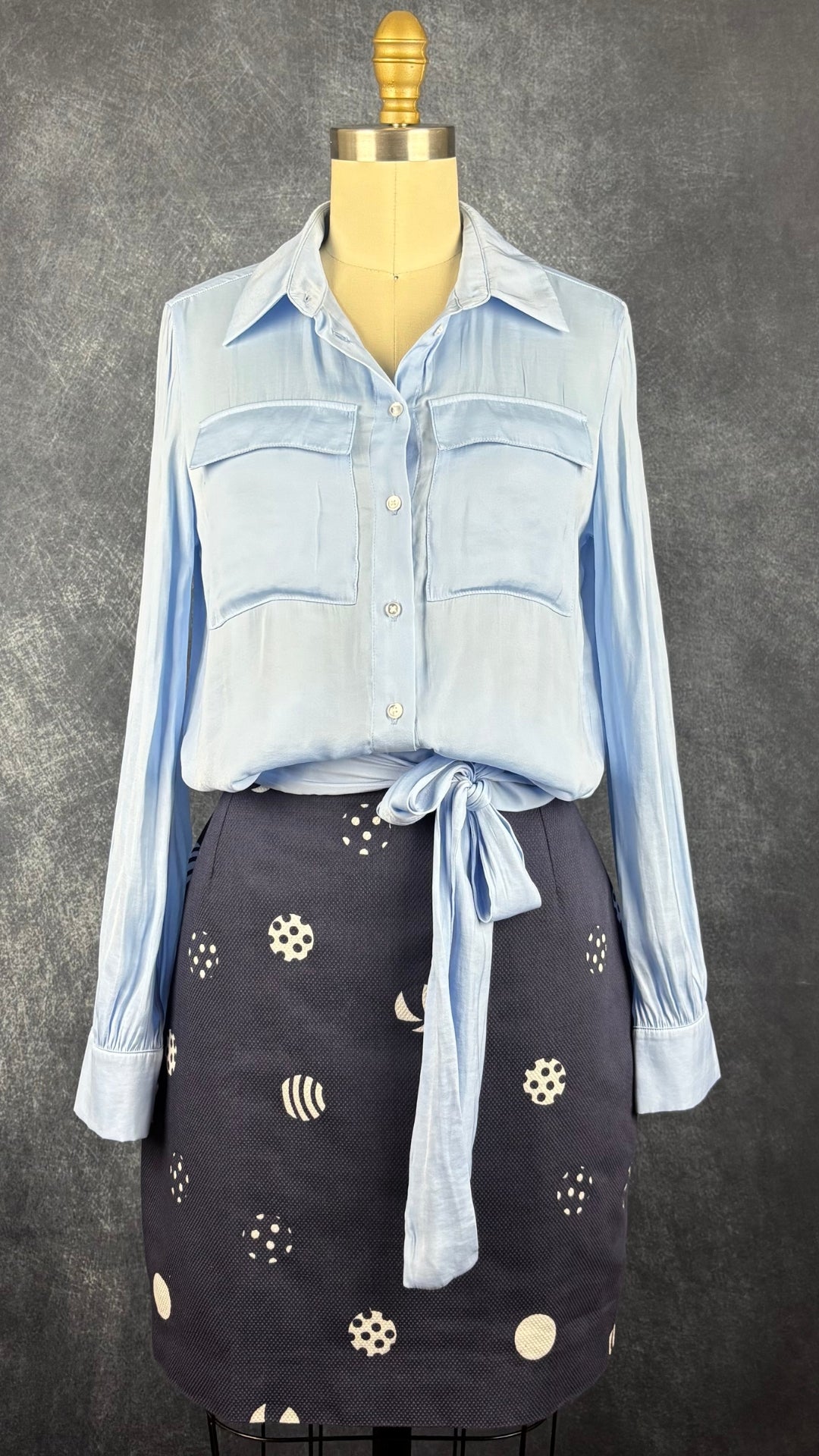 Blouse satinée bleu doux à taille soulignée de deux bandes de tissu à nouer, Tristan, taille xs. Vue de l'agencement avec la jupe marine à motifs de ballons.