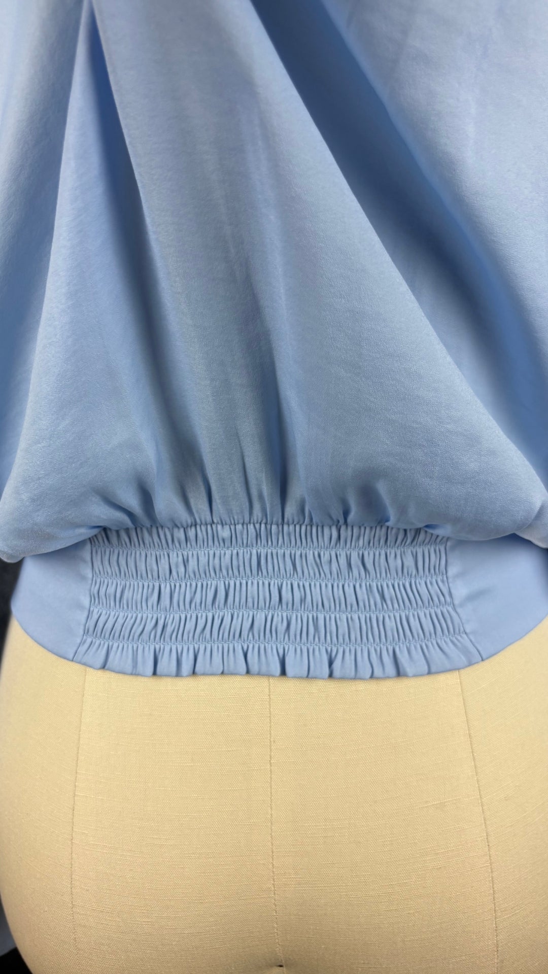 Blouse satinée bleu doux à taille soulignée de deux bandes de tissu à nouer, Tristan, taille xs. Vue de près de la bande élastique ruchée au bas du dos.