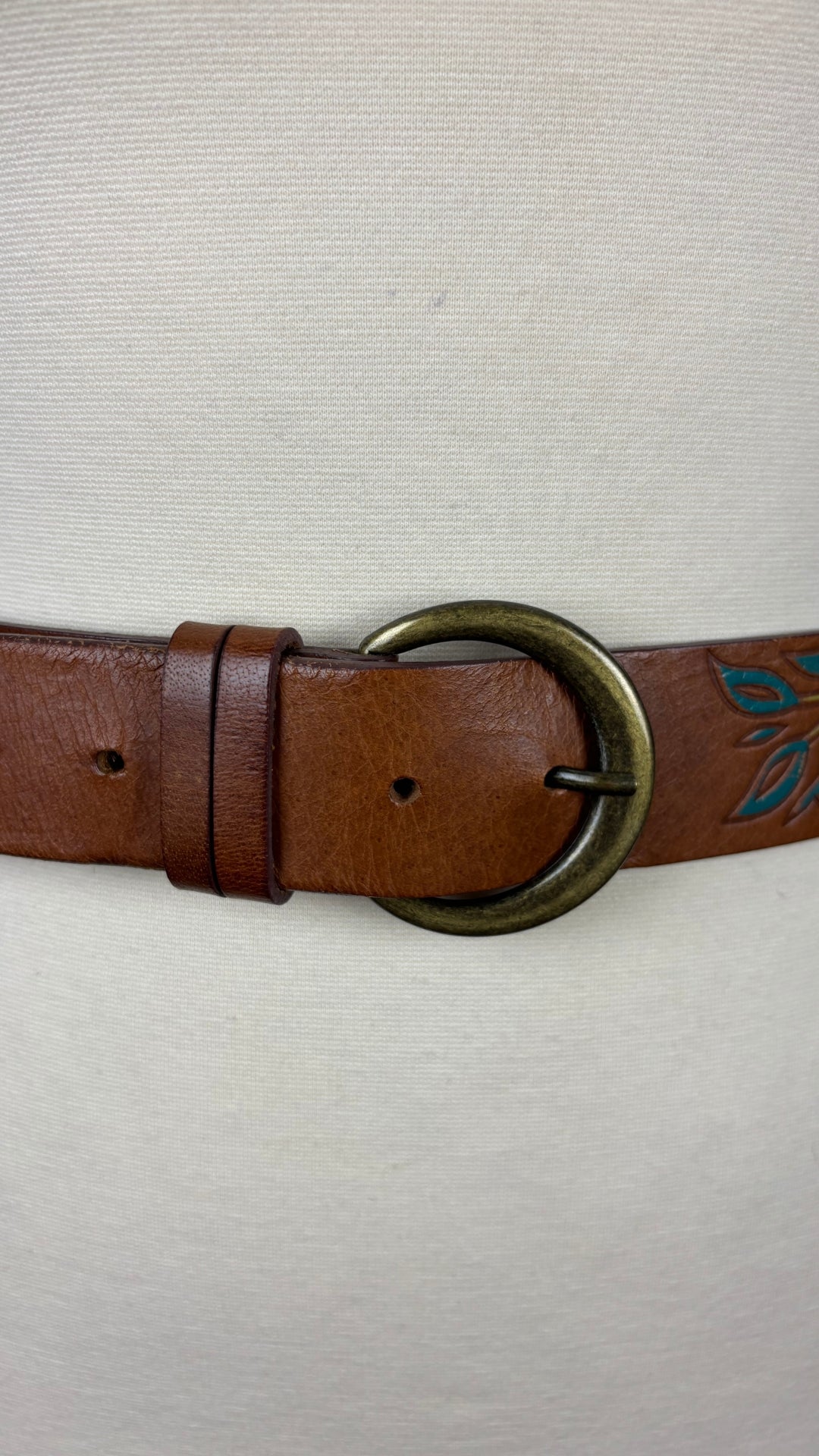 Ceinture en cuir brun à motifs floraux 3 Corone, taille small. Vue de près de la boucle de la ceinture, sur le mannequin.