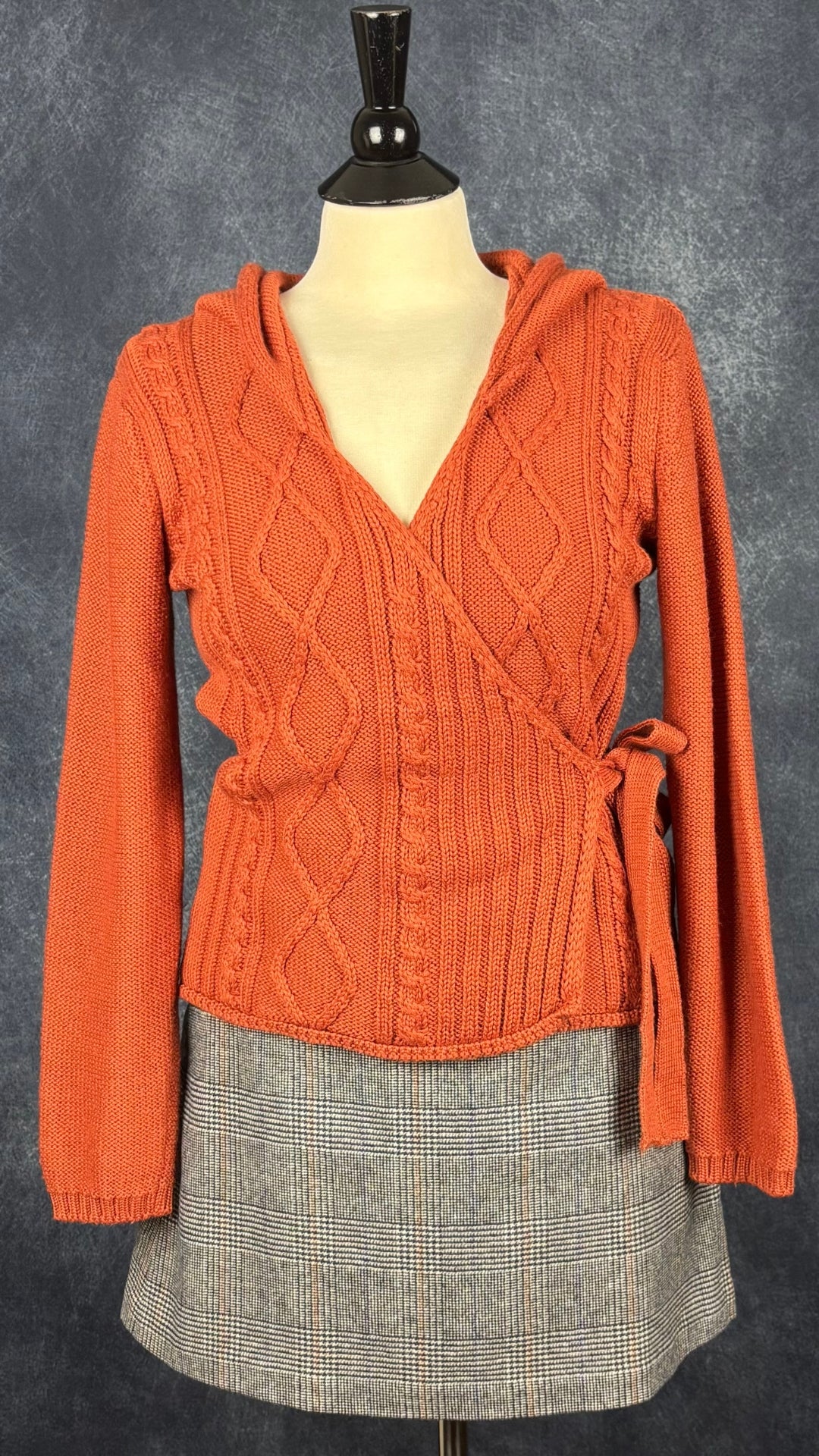 Chandail cache-coeur en tricot à capuchon couleur rouille Berretti, taille medium. Vue de l'agencement avec la jupe à carreaux Wilfred.