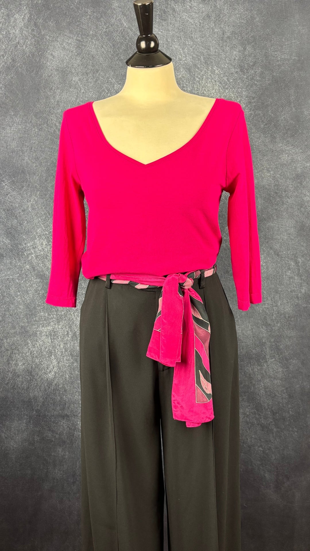 Chandail à col large en V rose fuchsia Isabelle Elie Boutique, taille estimée à s/m. Vue de l'agencement avec le pantalon noir magnifique Filippa K et le foulard à motifs fuchsia Cléo.