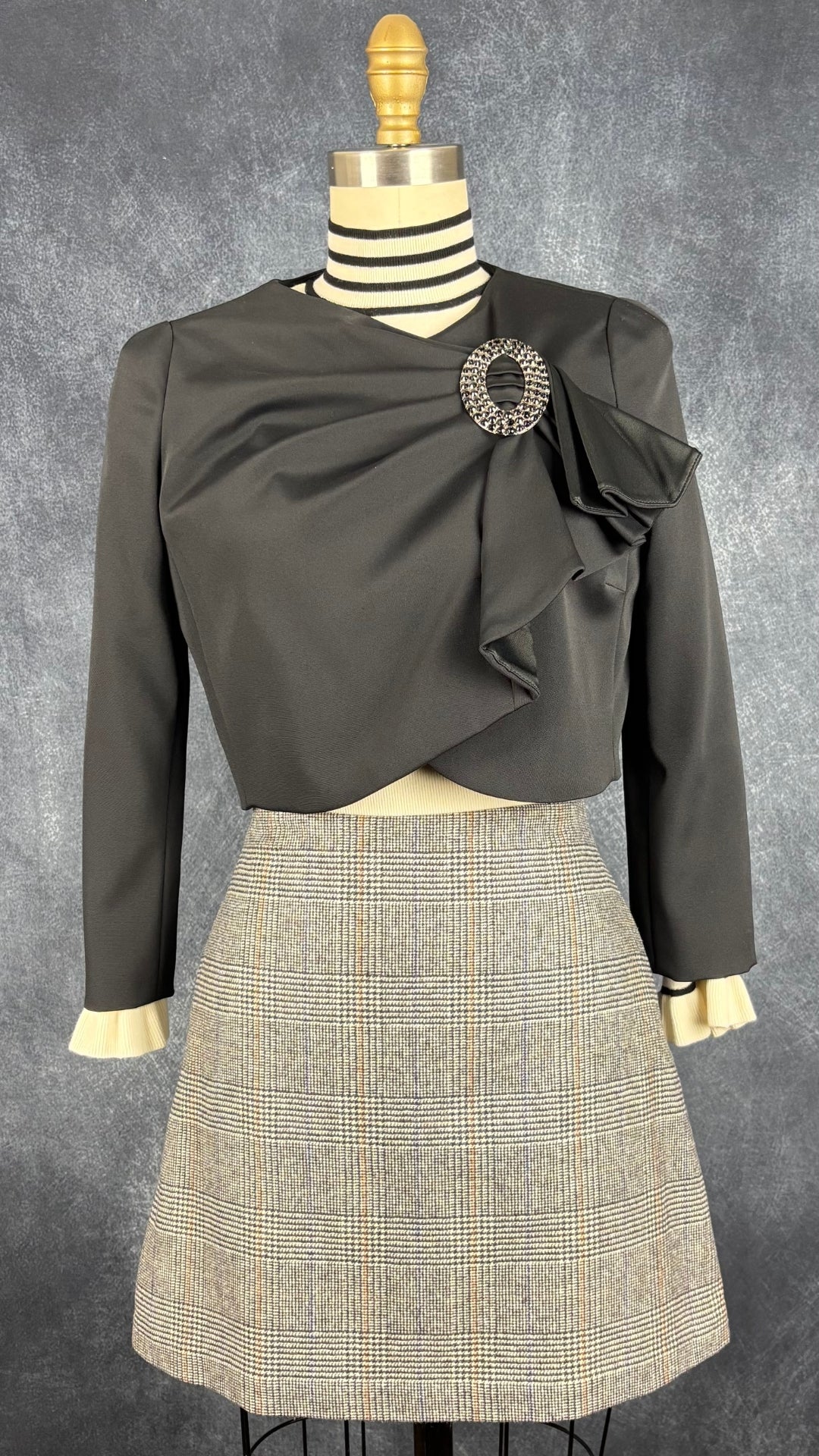 Chandail crème à col montant à ourlets à rayures noires et argentées Tristan, taille small. Vue de l'agencement avec la jupe à carreaux Wilfred et la veste noire Luisa Spagnoli.