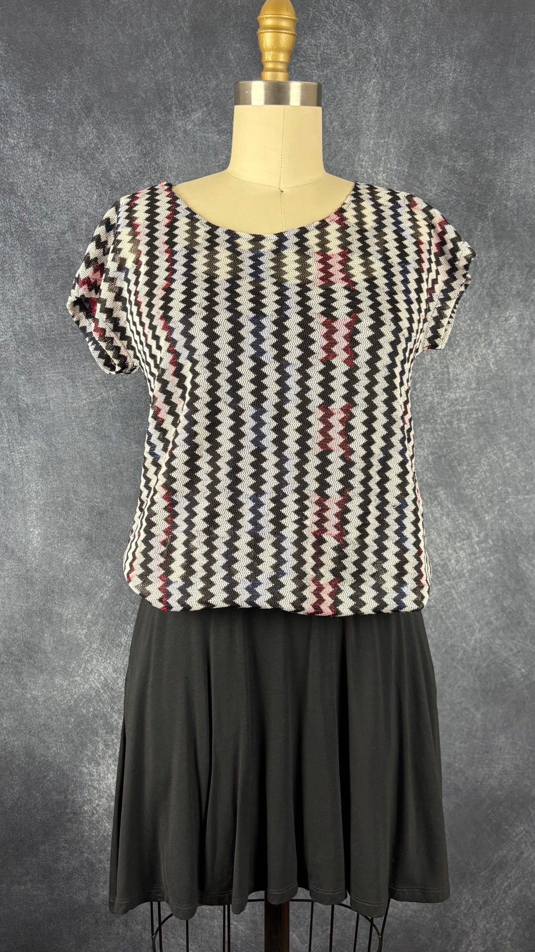Chandail diaphane à motifs de zigzags colorés Riani, taille estimée à small/medium. Vue de l'agencement avec la robe noire simple.