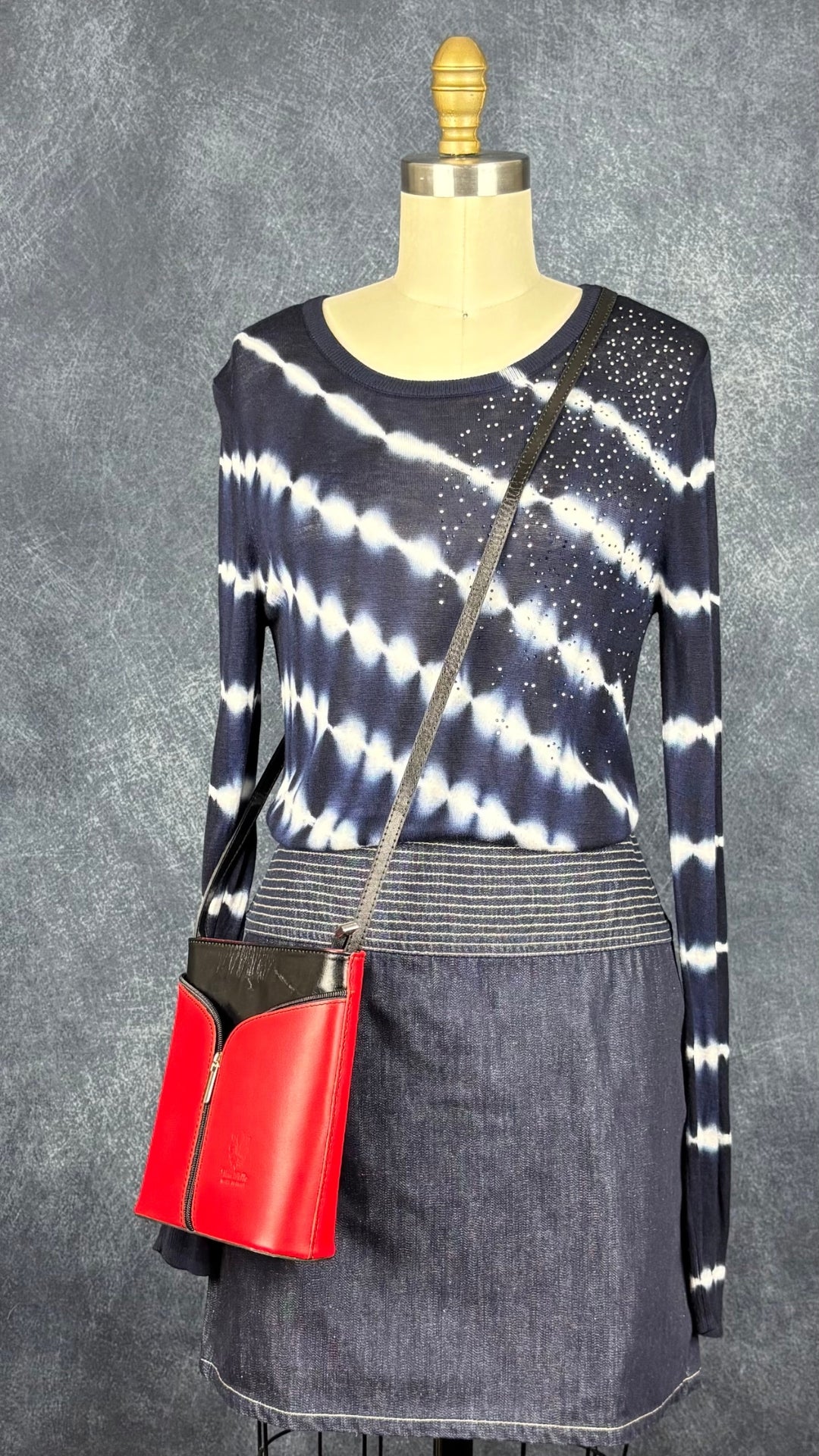 Chandail bleu et blanc en fin tricot tie dye avec brillants à l'épaule Desigual, taille medium. Vue de l'agencement avec la jupe Versace et le sac en cuir rouge et noir.