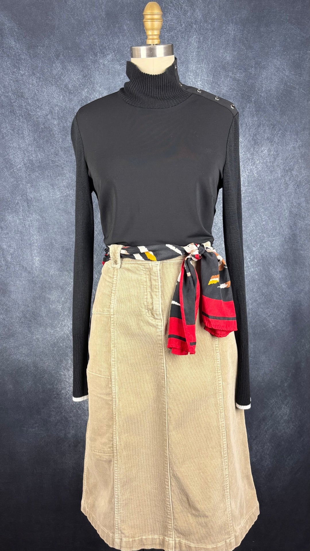 Chandail noir bi-matière à col montant I by Iris Setlakwe, taille small. Vue de l'agencement avec la jupe en velours côtelé beige et le foulard à motifs colorés Monique Martin.