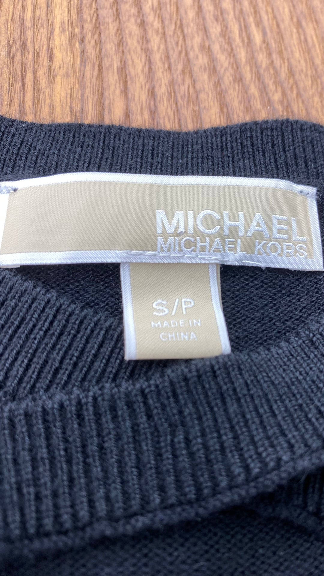 Chandail noir en tricot à encolure à ouvertures majestueuses Michael Kors, taille small. Vue de l'étiquette de marque et taille.