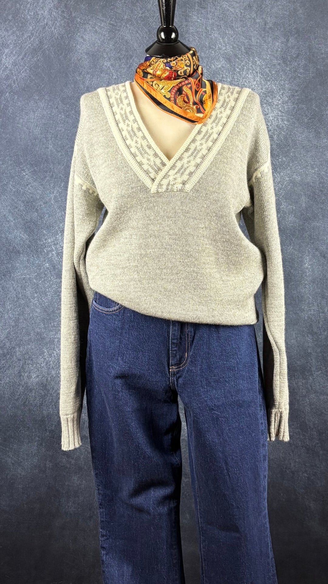 Chandail norvégien gris et crème en laine vierge et col en V, Dale of Norway, taille large. Vue de l'agencement avec le jeans foncé galbé et le foulard coloré.