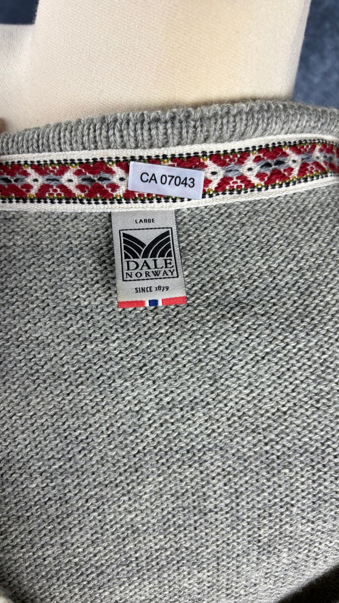 Chandail norvégien gris et crème en laine vierge et col en V, Dale of Norway, taille large. Vue de l'étiquette.