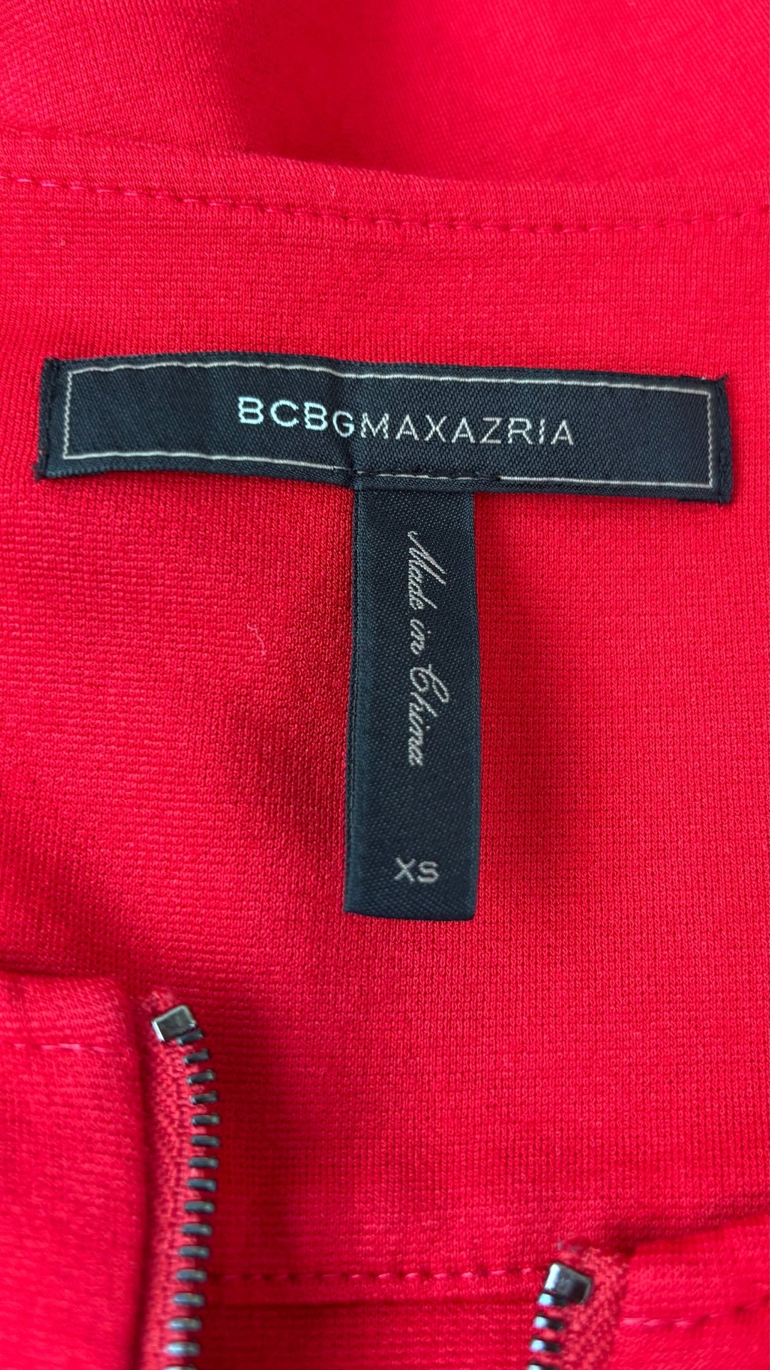 Chandail rouge en ponte à ourlet péplum asymétrique BCBG MaxAzria, taille xs. Vue de l'étiquette.