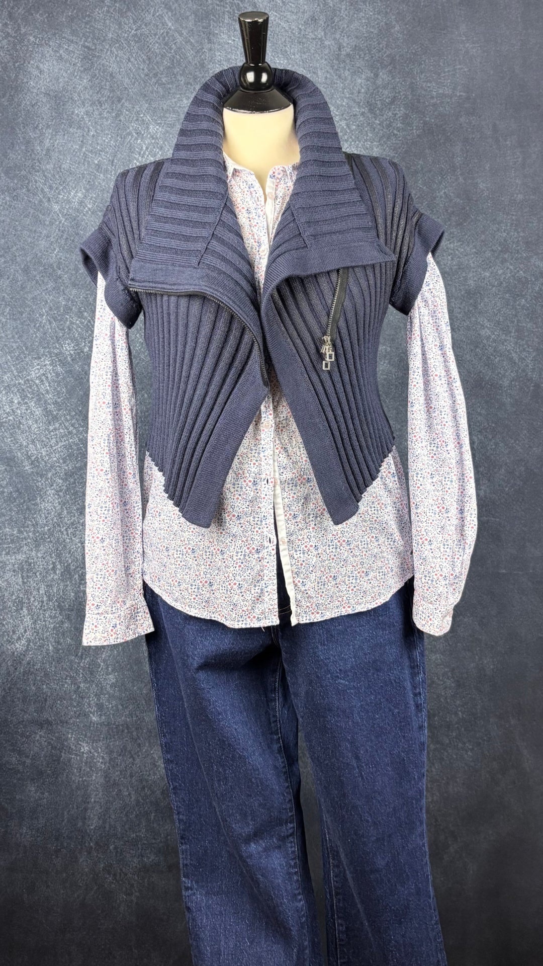 Chandail en tricot asymétrique bleu acier et noir avec fermeture à glissière et col 3 façons Sarah Pacini, xs à medium. Vue de l'agencement avec le chemisier floral Saint James et le jeans Denim Forum foncé galbé.