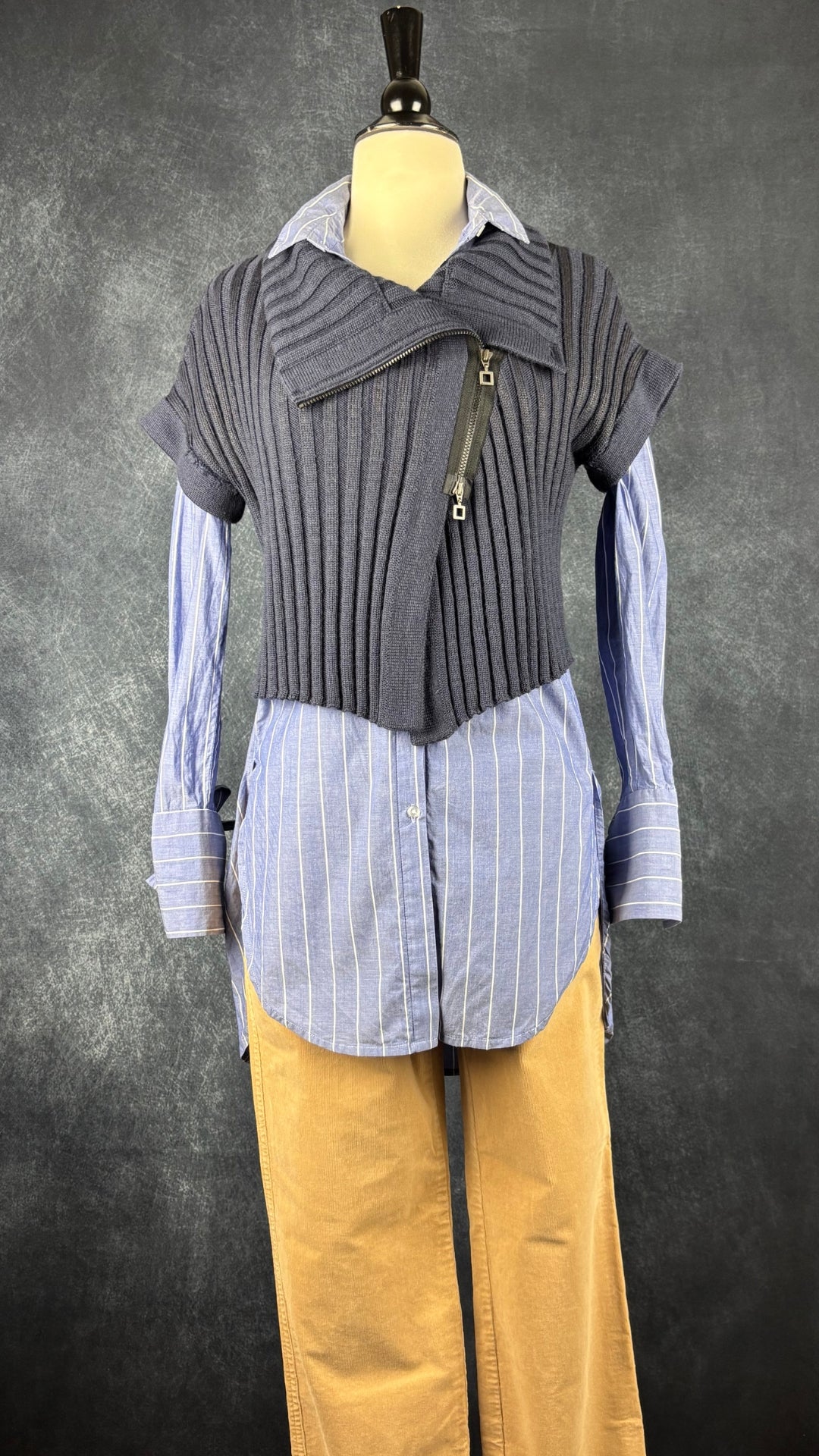 Chandail en tricot asymétrique bleu acier et noir avec fermeture à glissière et col 3 façons Sarah Pacini, xs à medium. Vue de l'agencement avec le chemisier long à rayures InWear et le pantalon beige en velours côtelé Olsen.