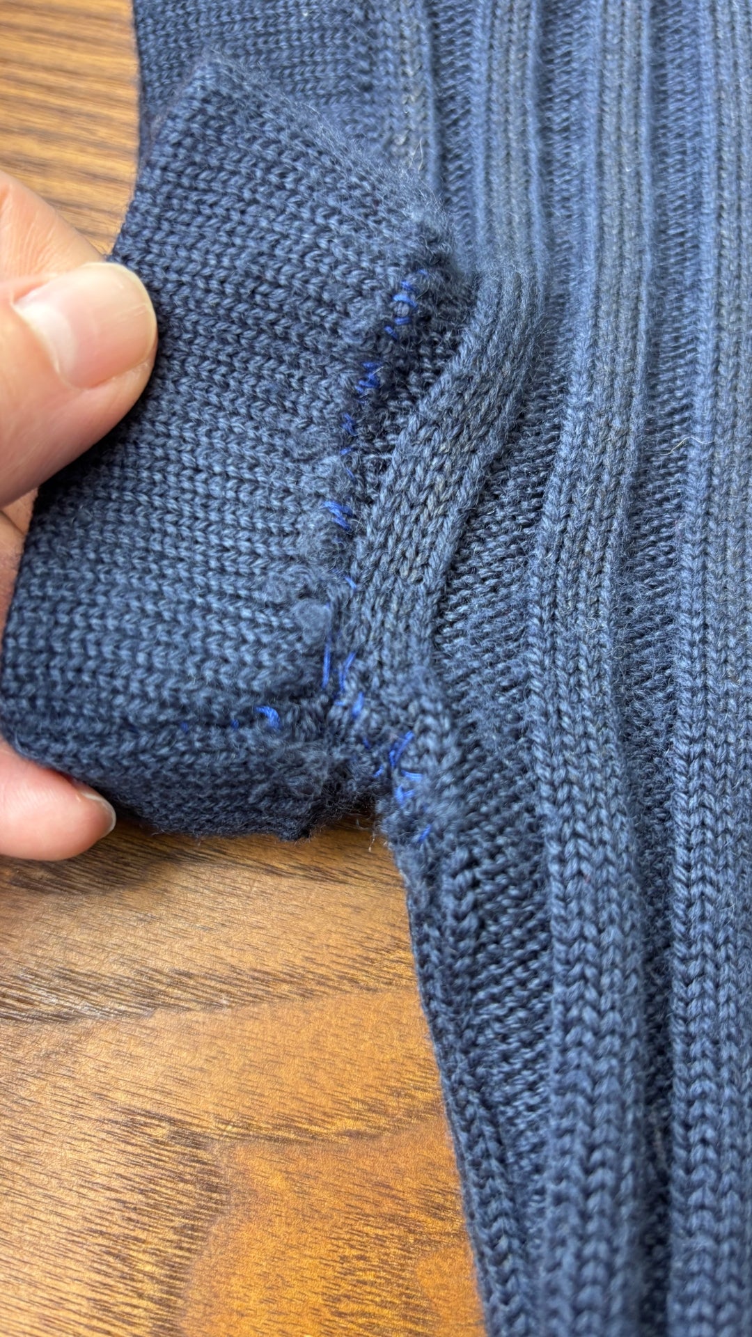 Chandail en tricot asymétrique bleu acier et noir avec fermeture à glissière et col 3 façons Sarah Pacini, xs à medium. Vue de près d'une des imperfections aux manches.
