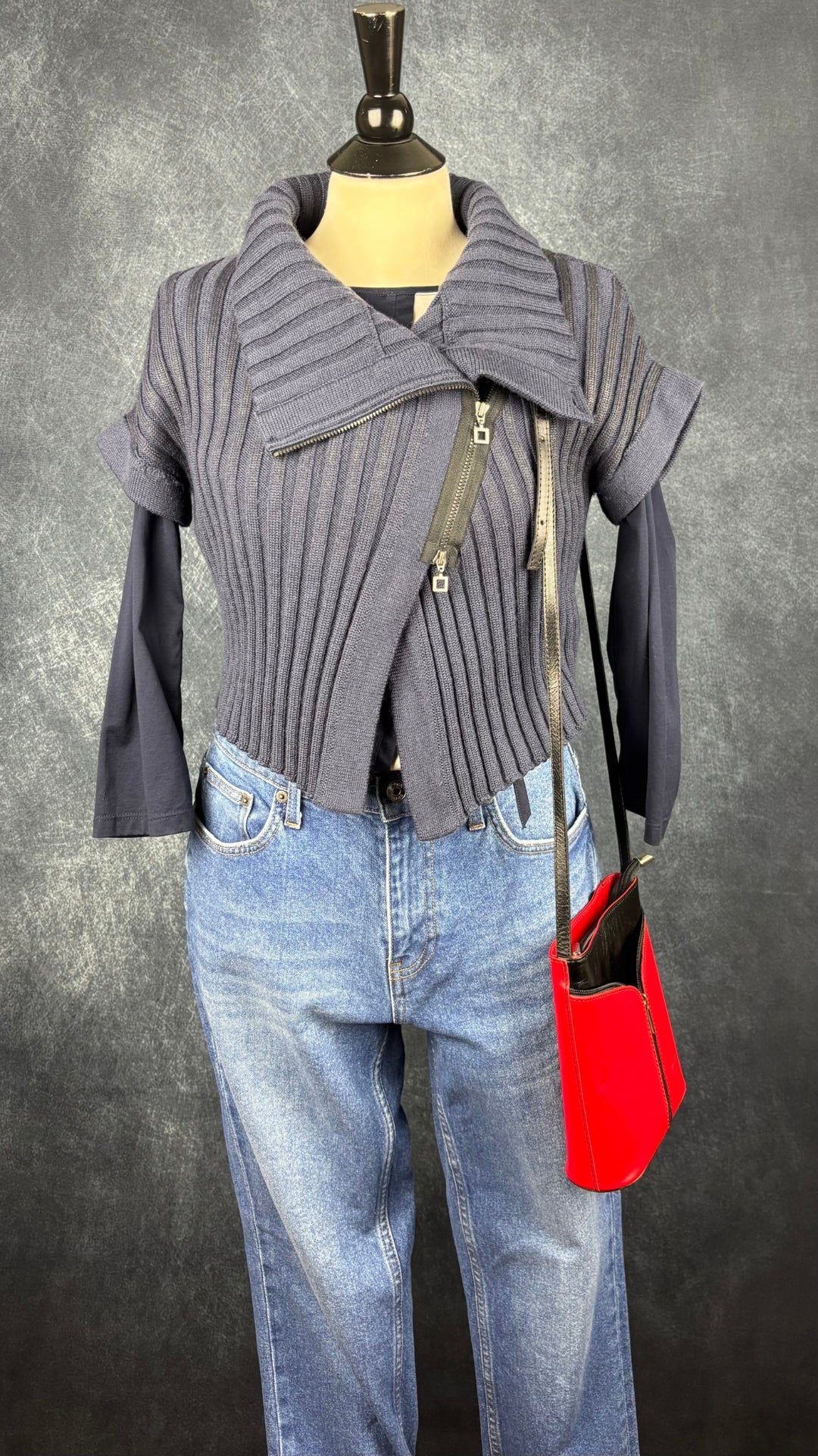 Chandail en tricot asymétrique bleu acier et noir avec fermeture à glissière et col 3 façons Sarah Pacini, xs à medium. Vue de l'agencement avec le sac à main rouge et noir Vera Pelle, le jeans Yoga et le chandail marine et crème Gerry Weber.