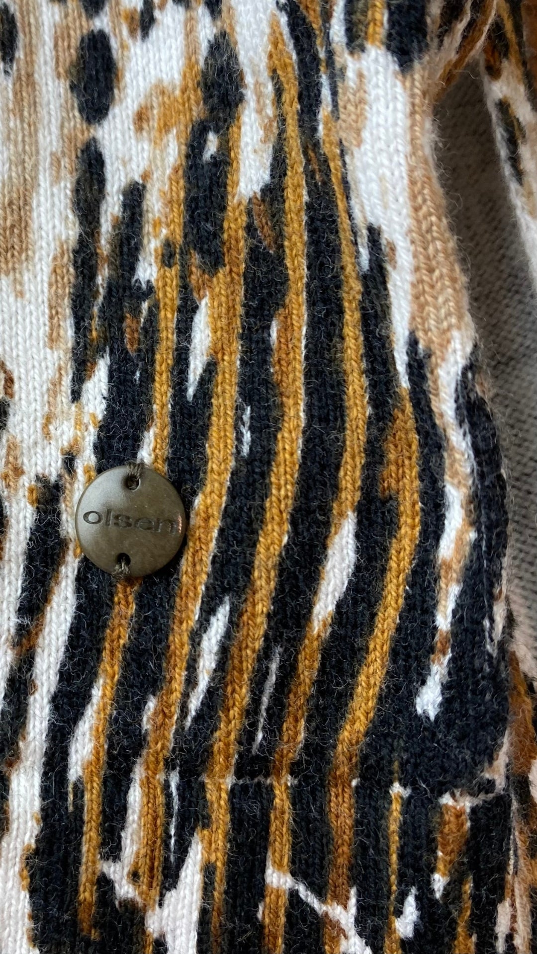 Chandail tricot col v motif style léopard Olsen, taille s/m. Vue du détail métallique gravé au nom de la marque.
