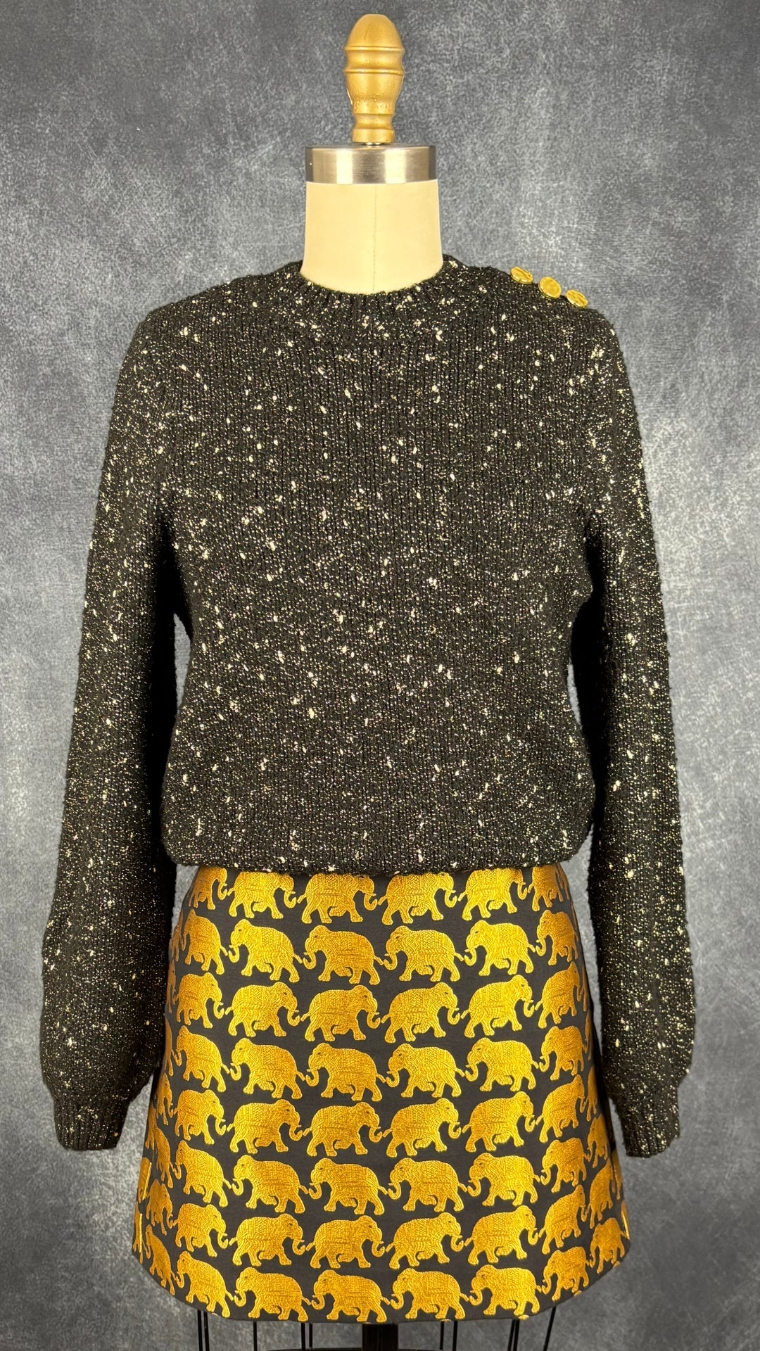 Chandail en tricot noir et doré Ichi, taille small. Vue de l'agencement avec la jupe à motifs d'éléphants dorés J.Crew.