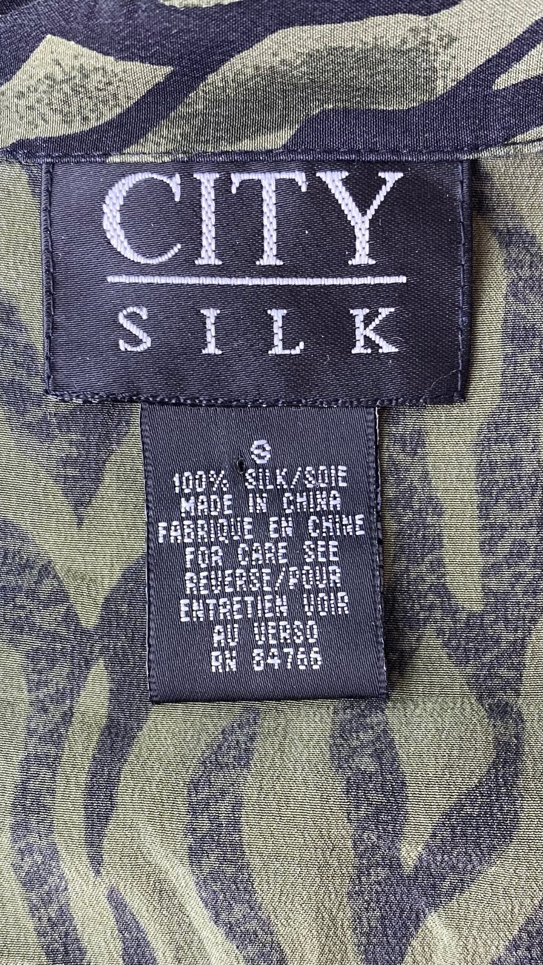 Chemisier en soie à zébrures vertes et noires City Silk, taille small (xs). Vue de l'étiquette de marque, taille et composition.
