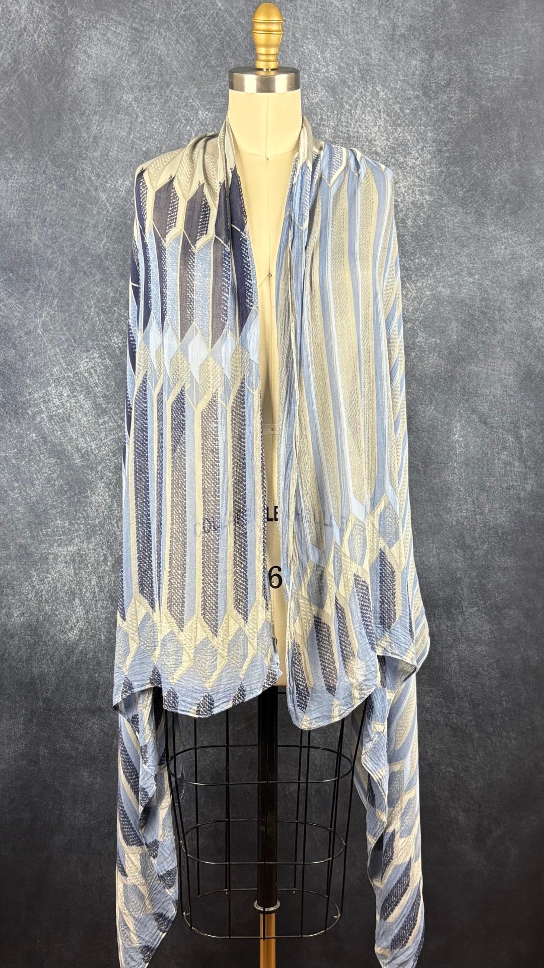 Foulard fin à motifs géométriques gris, bleu doux, bleu denim, marine Sandwich, grand rectangle. Vue du foulard déposé sur les épaules du mannequin.