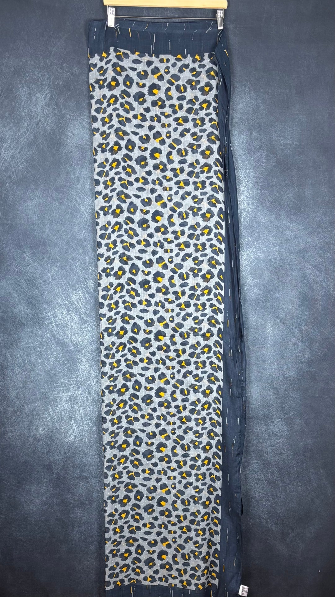 Foulard à motif animalier marine, bleu-gris et jaune ocre Sandwich, taille grand rectangle. Vue de face du foulard plié en deux sur un cintre.