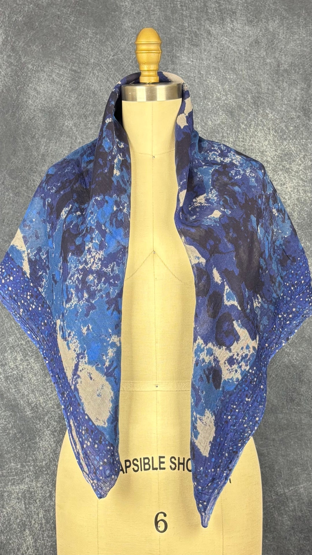 Foulard à motifs abstraits gris et bleu en viscose, Sandwich, taille grand rectangle. Vue du foulard porté sur les épaules, de face.
